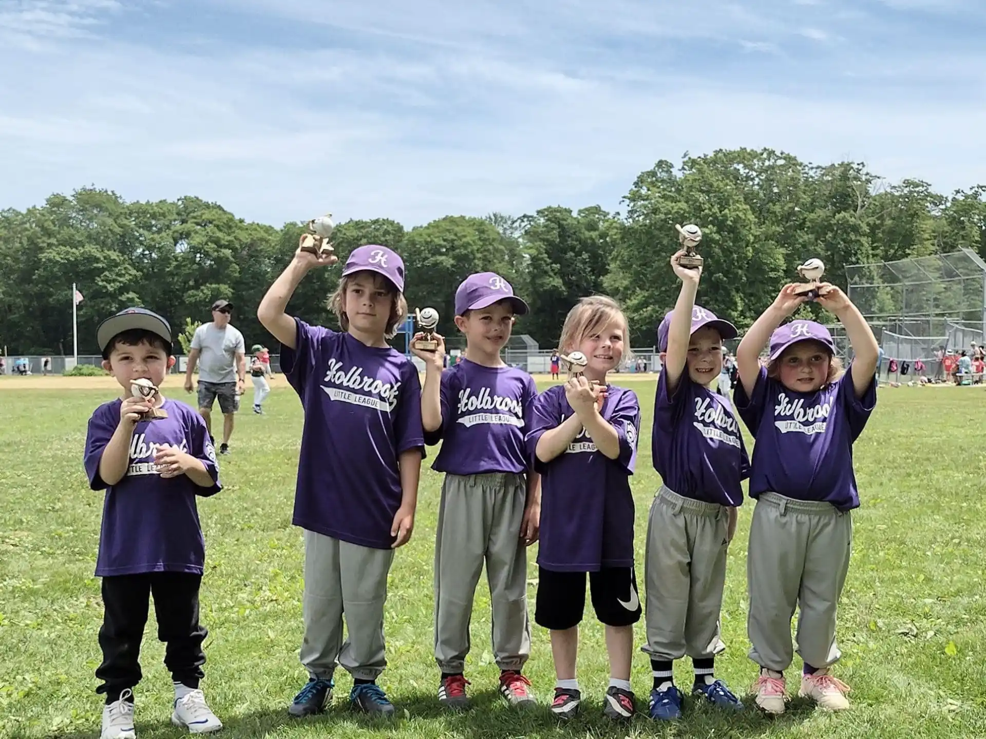 a group of kids wearing purple shirts and standing on grass