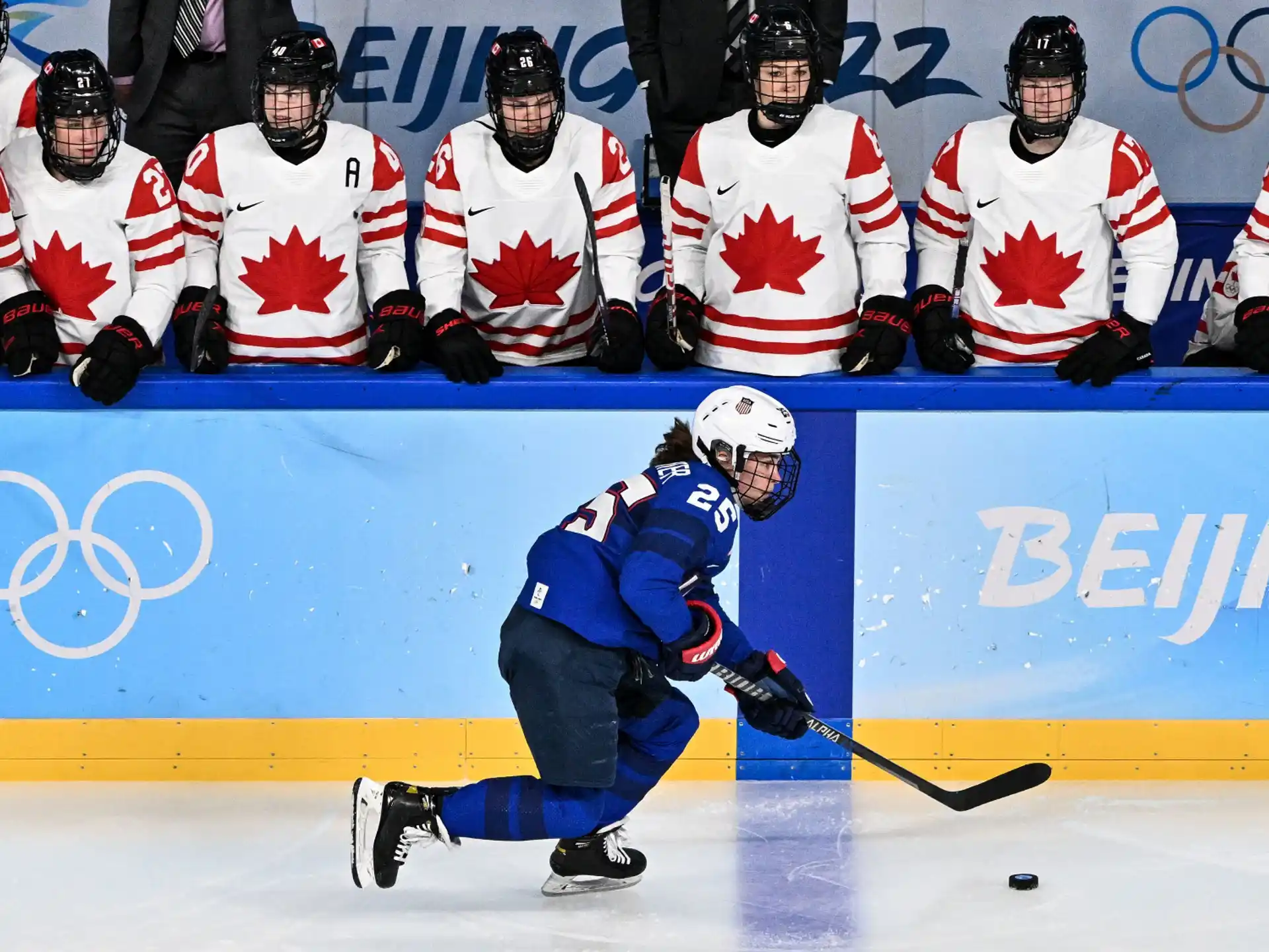 a hockey player in blue and white with a hockey stick in front of a group of people in
