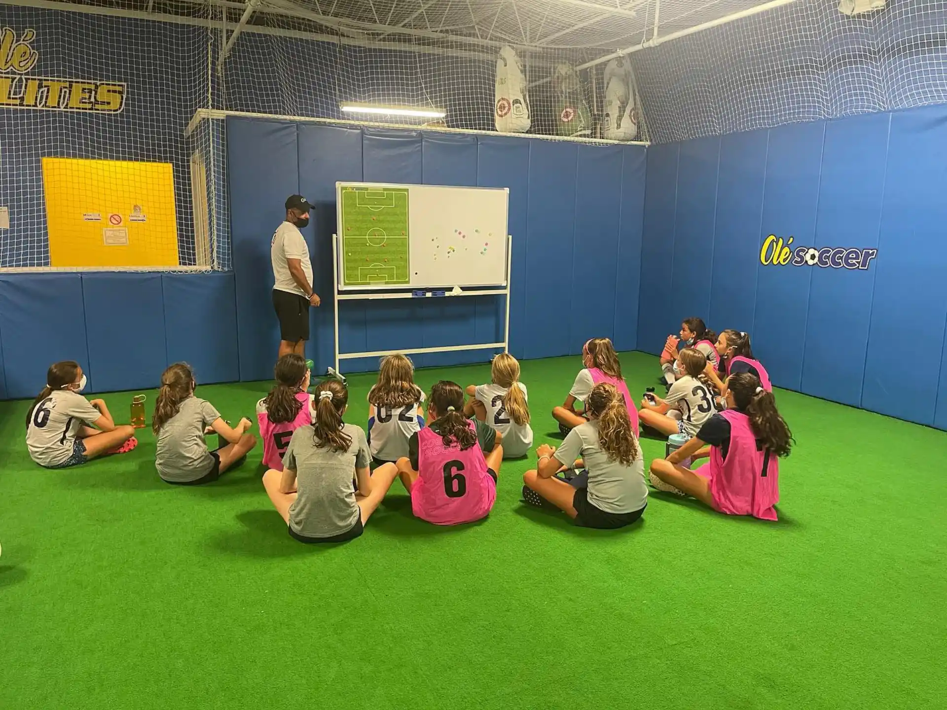 a group of children sitting on the floor in front of a person standing