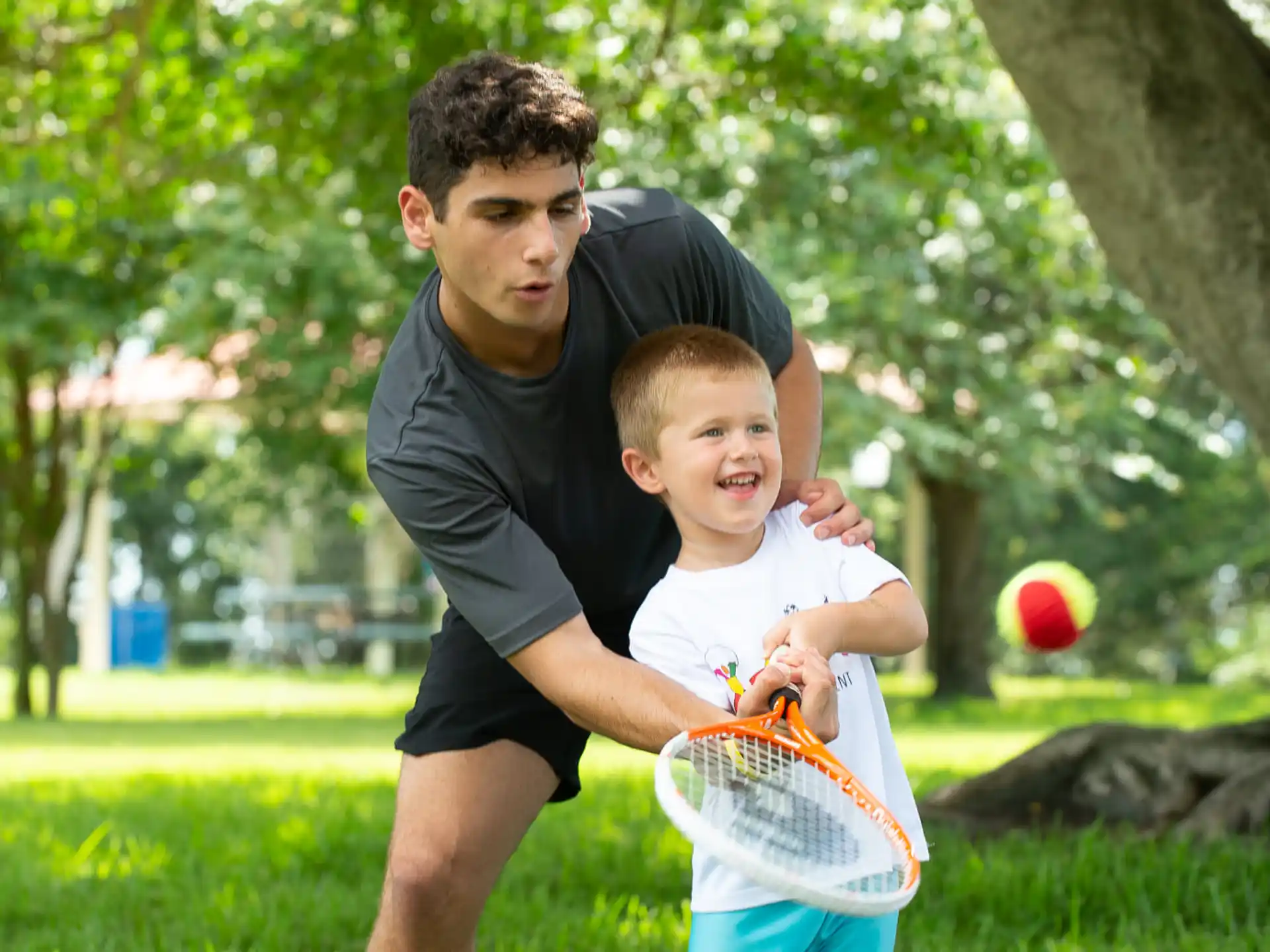 a person and a boy playing tennis