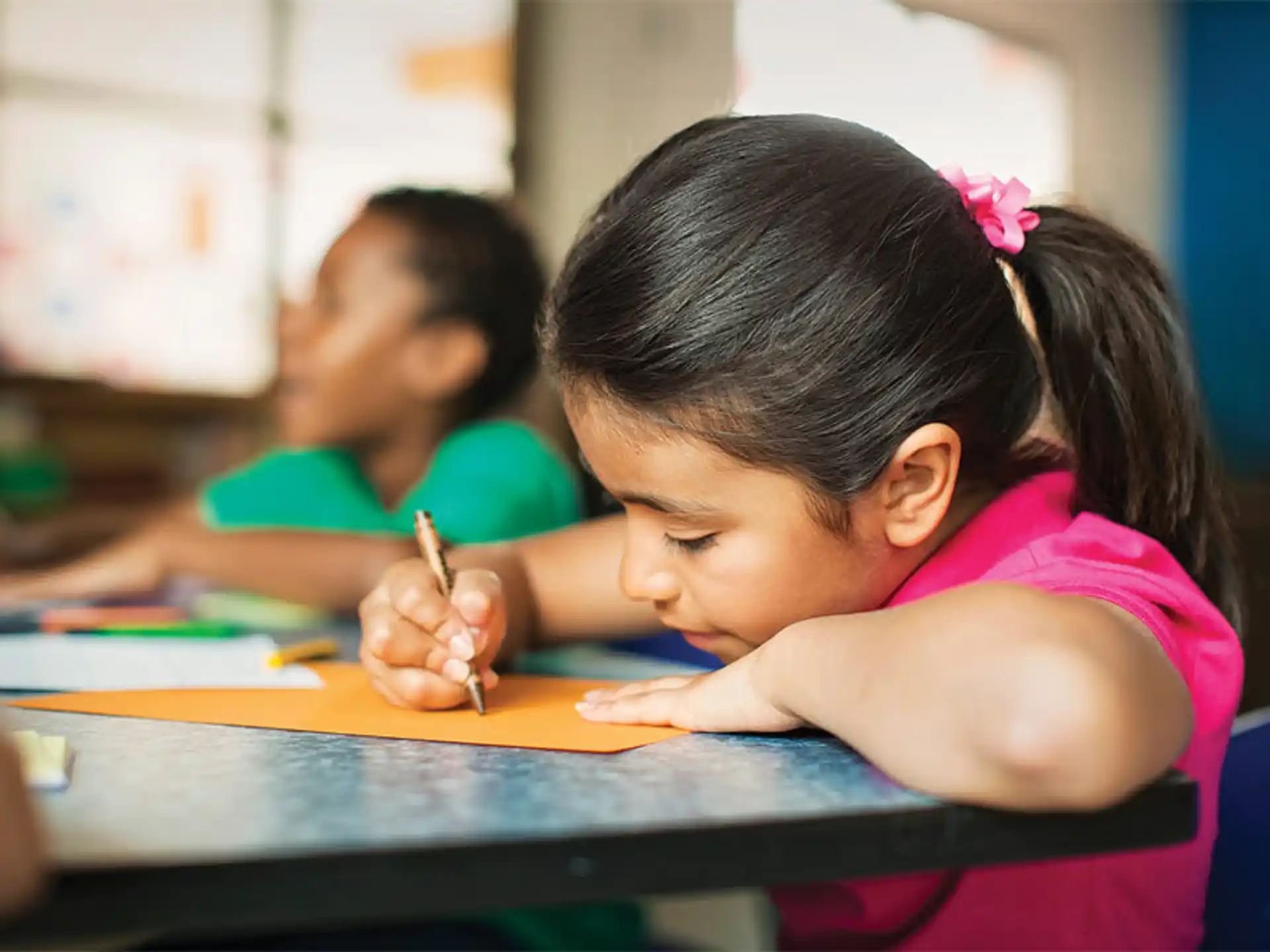 a young girl writing on a piece of paper