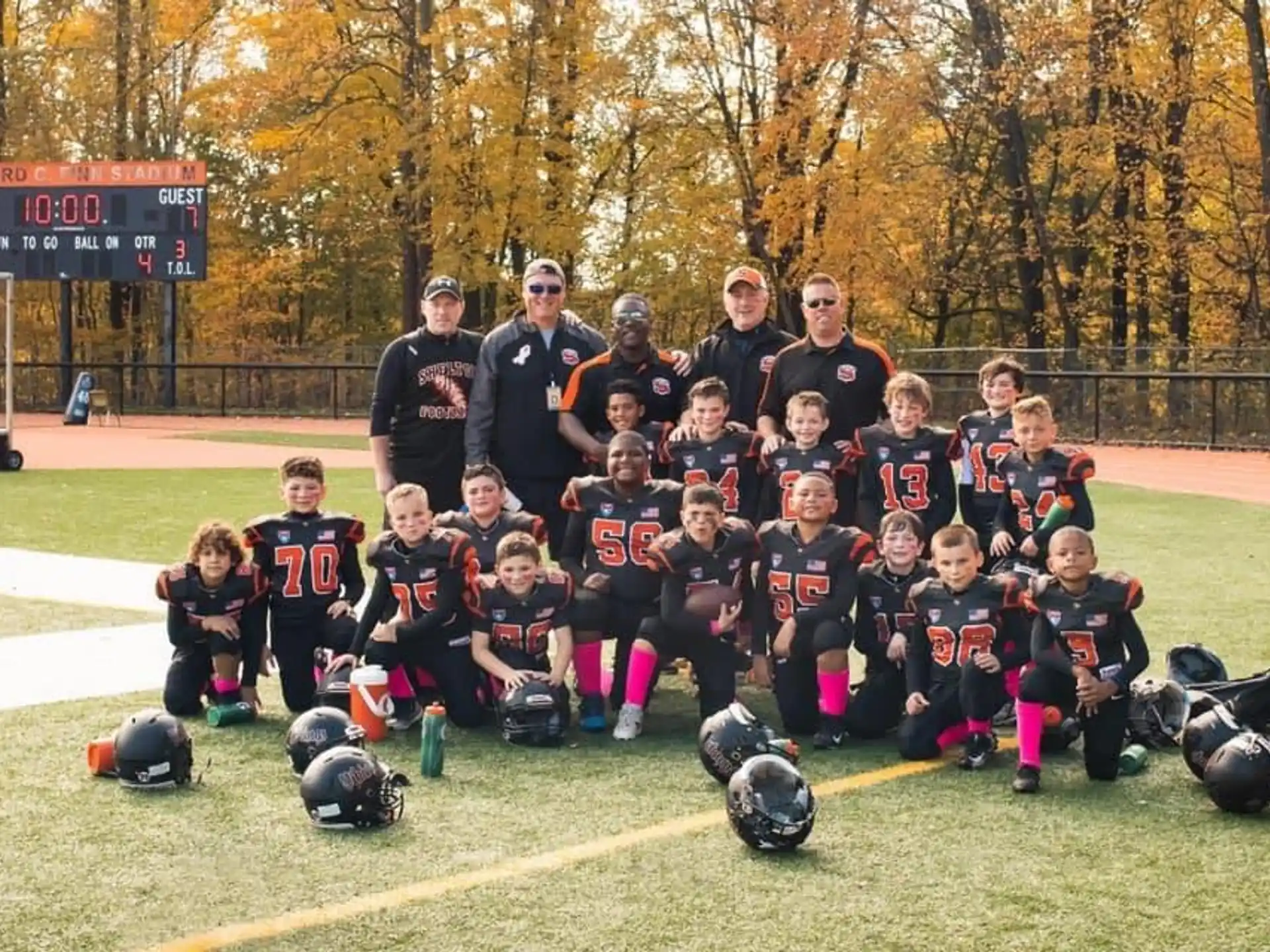 a group of kids posing for a photo with helmets on a field