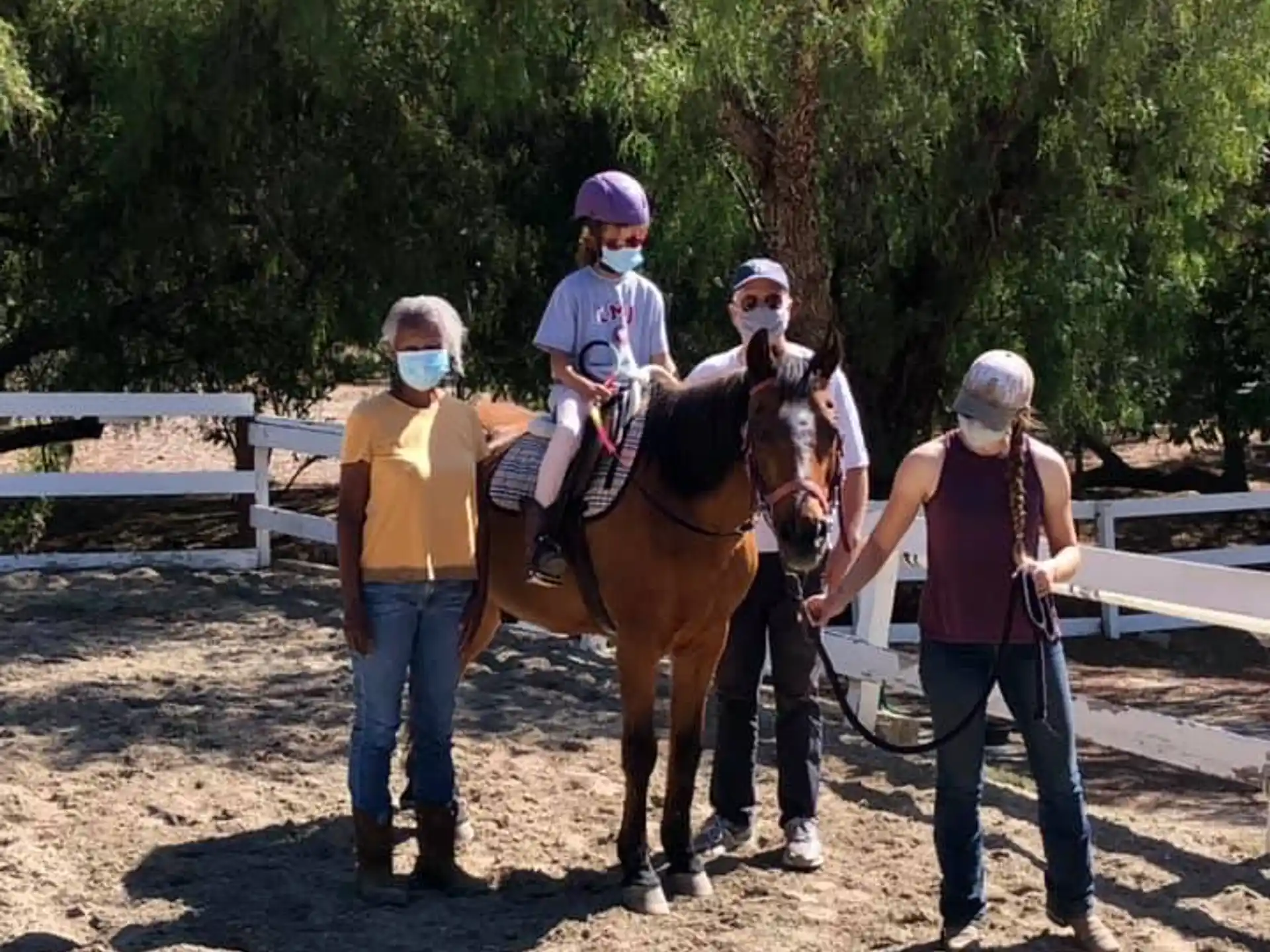 a group of people standing next to a horse with a person on it