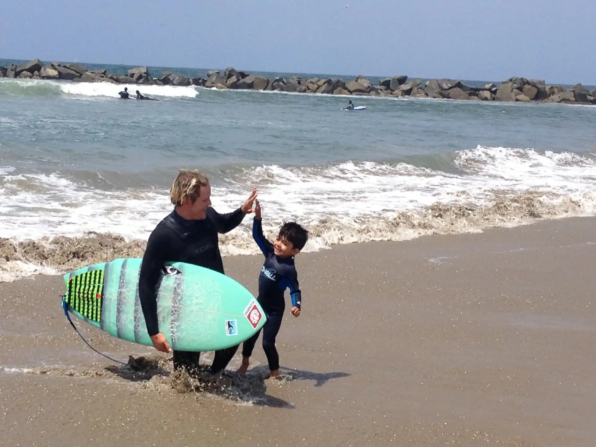 a person and a boy carrying surfboards on a beach