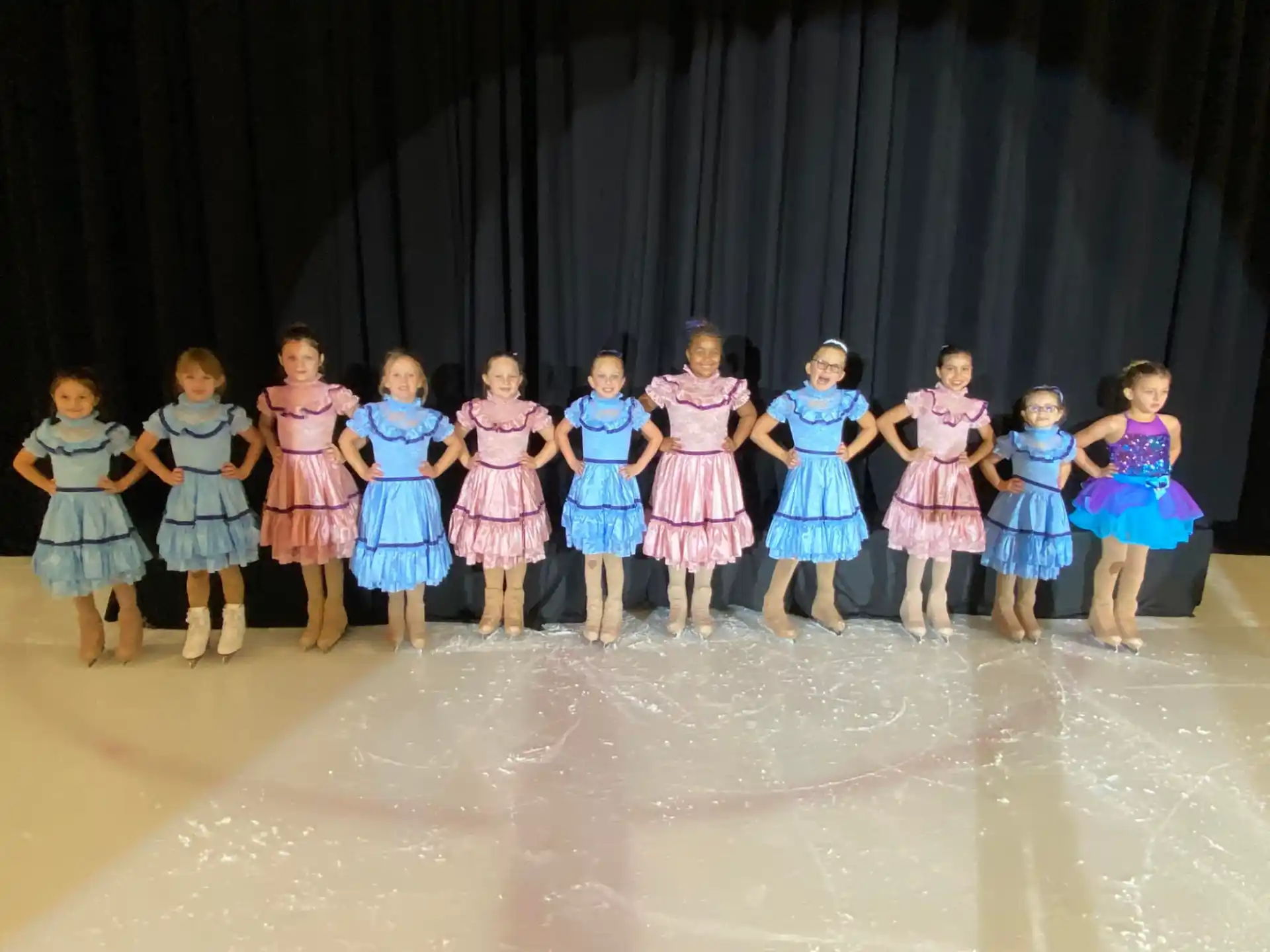 a group of girls in dresses on a stage