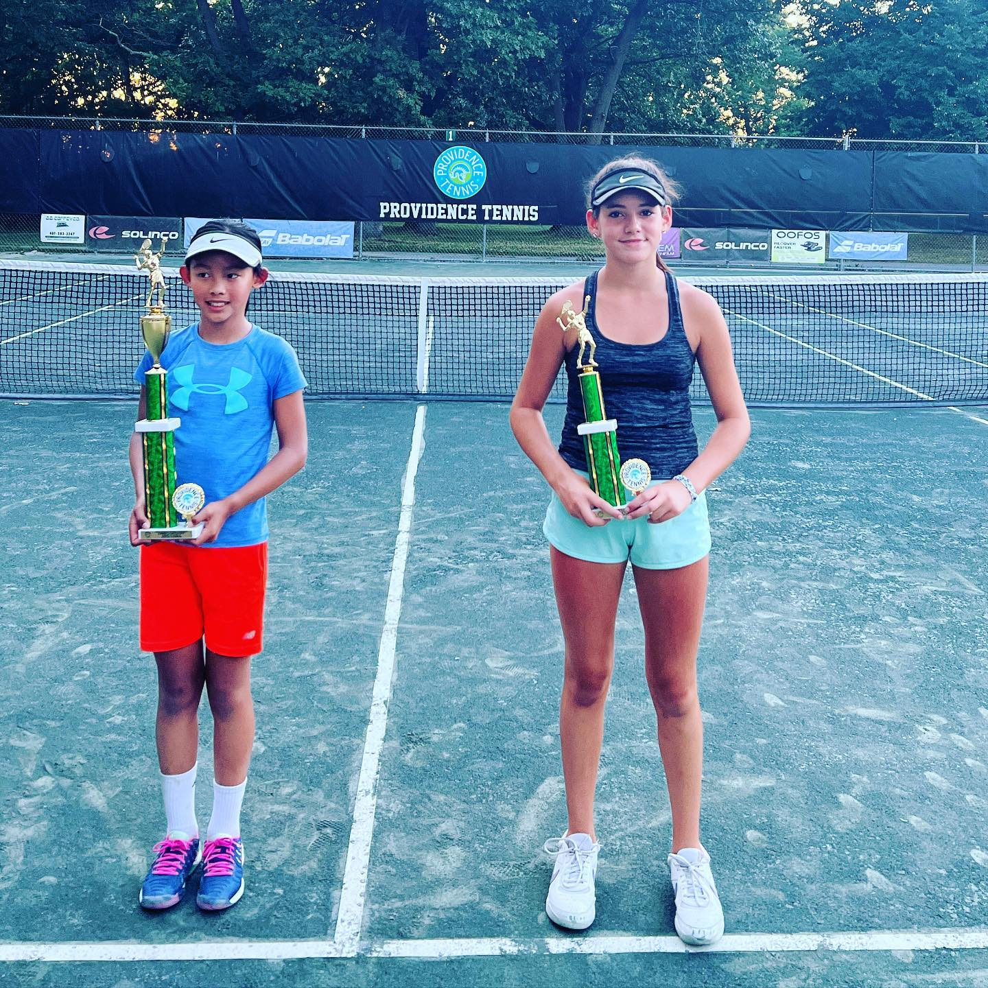a couple of women holding tennis rackets on a tennis court