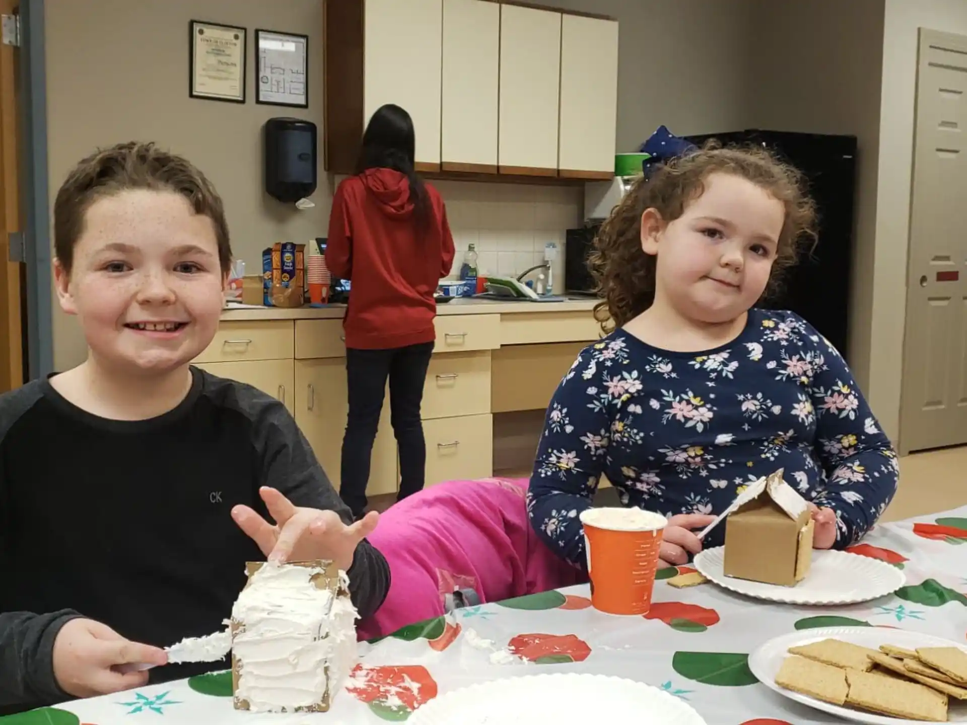 a couple of kids sitting at a table with food