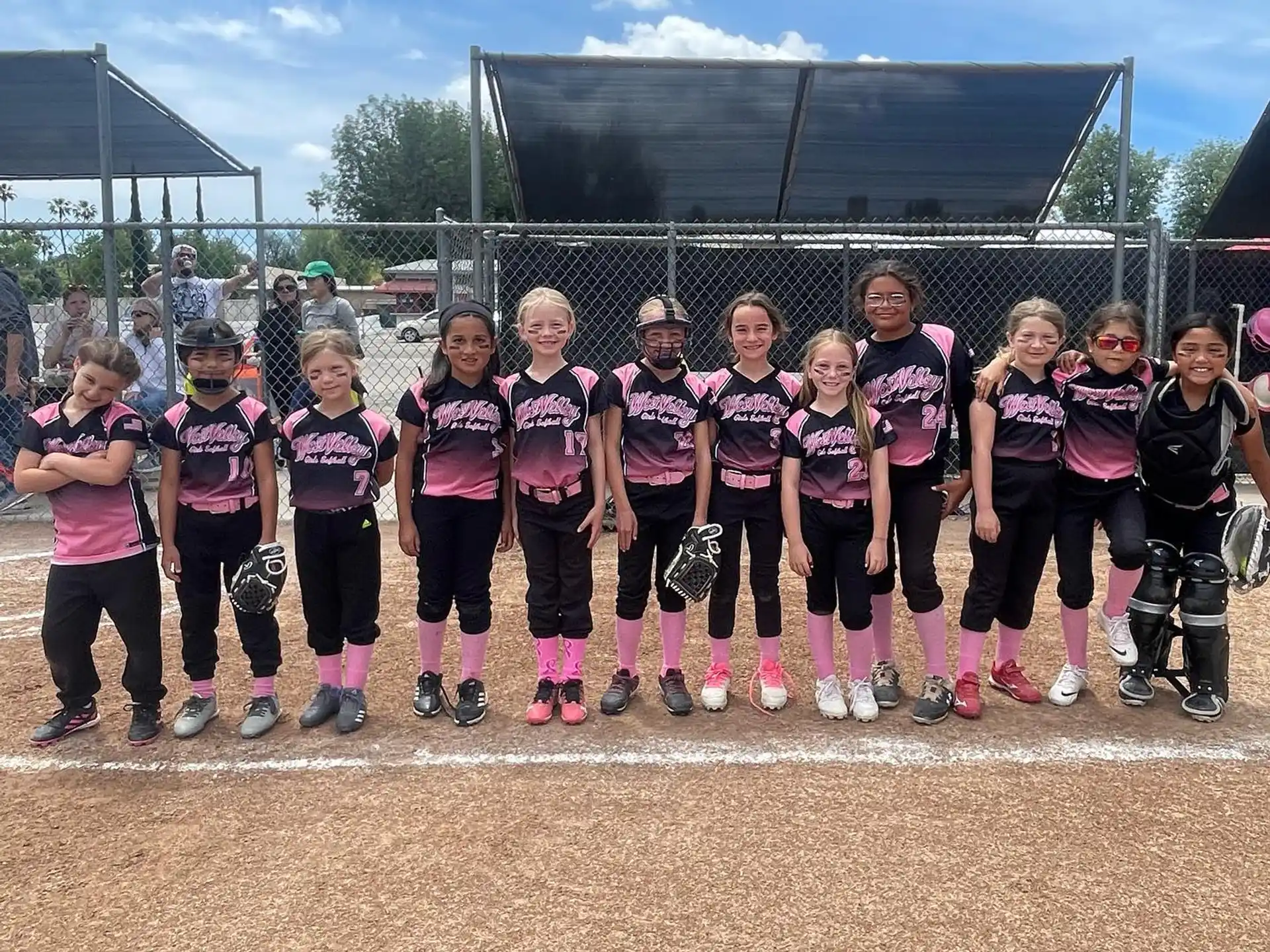 a group of girls in matching pink shirts and black pants