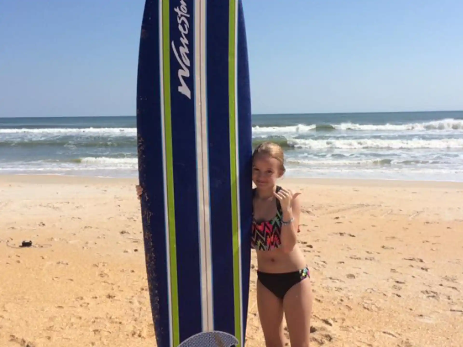 a woman standing next to a surfboard on a beach