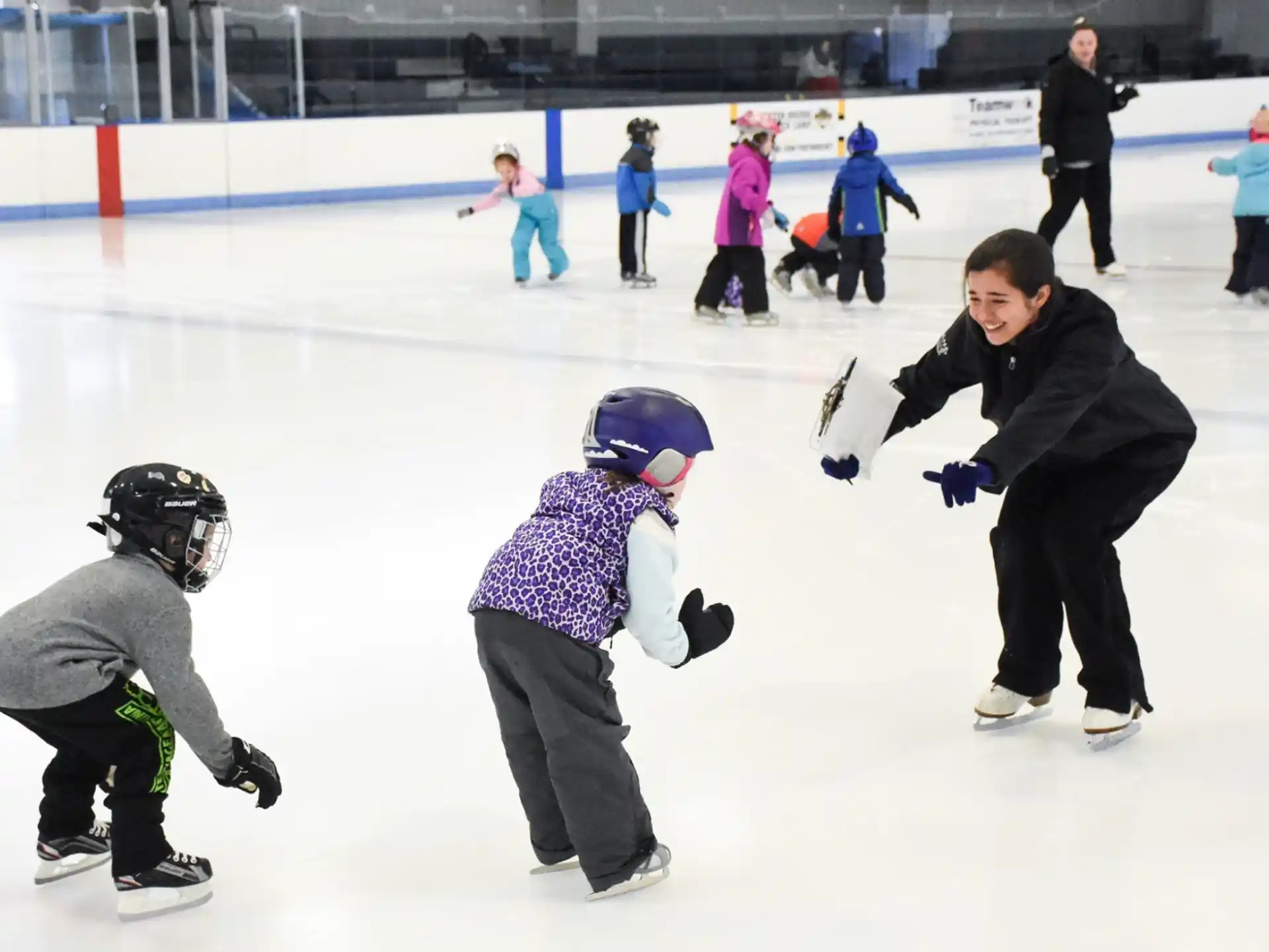 a person and a couple of kids on an ice rink with an audience
