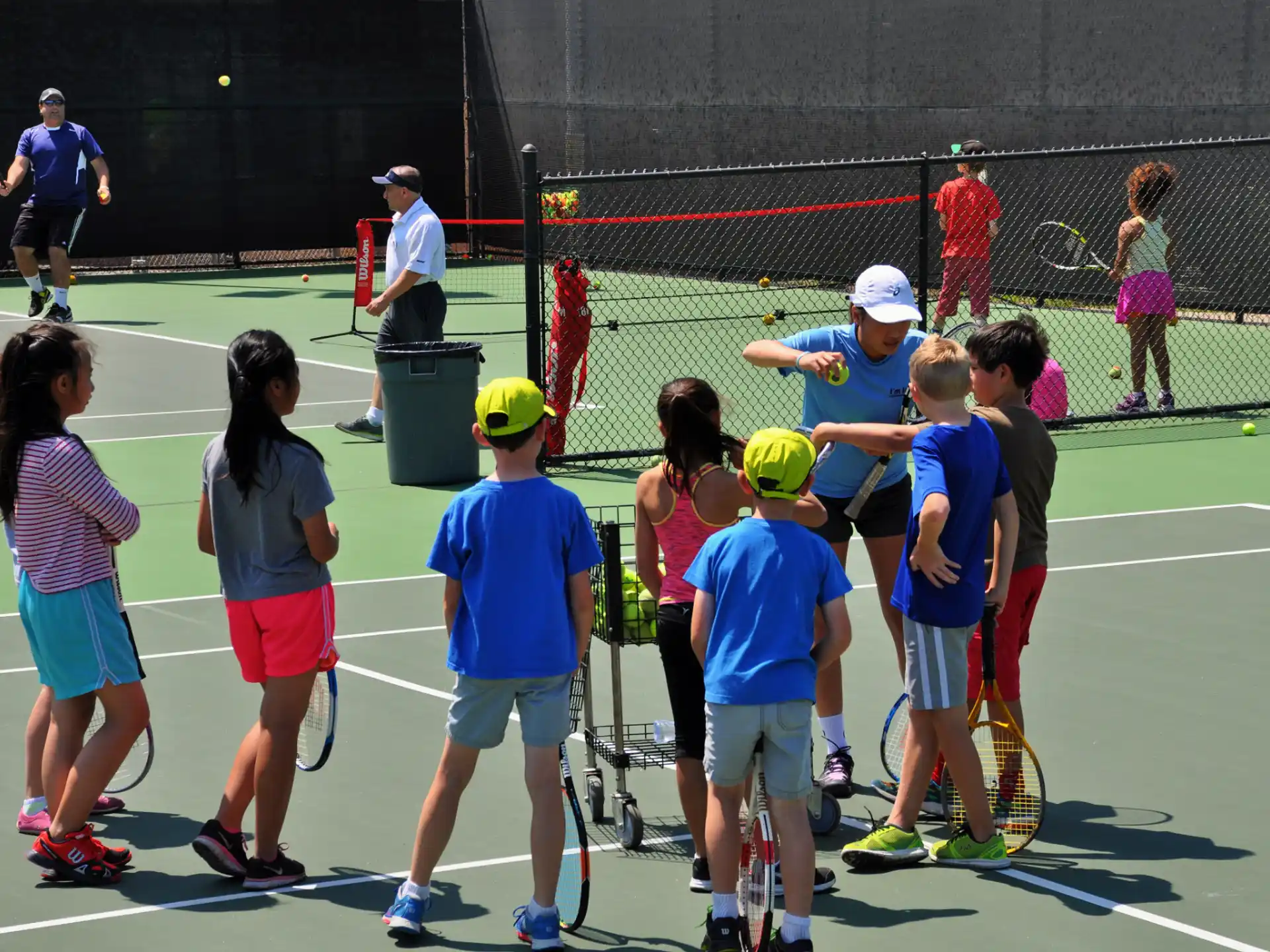 a group of kids stand on a tennis court