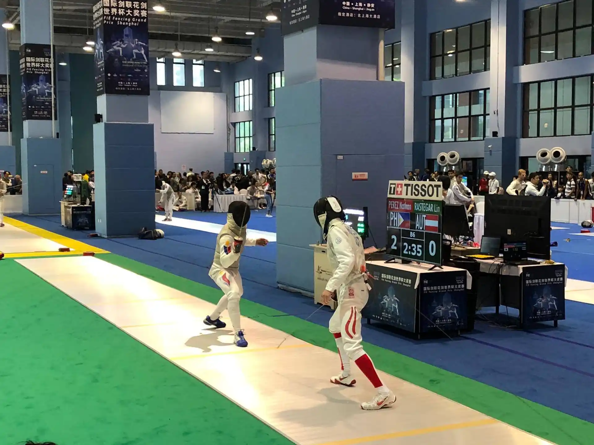 a couple of people in white uniforms on a green mat in front of a crowd of people