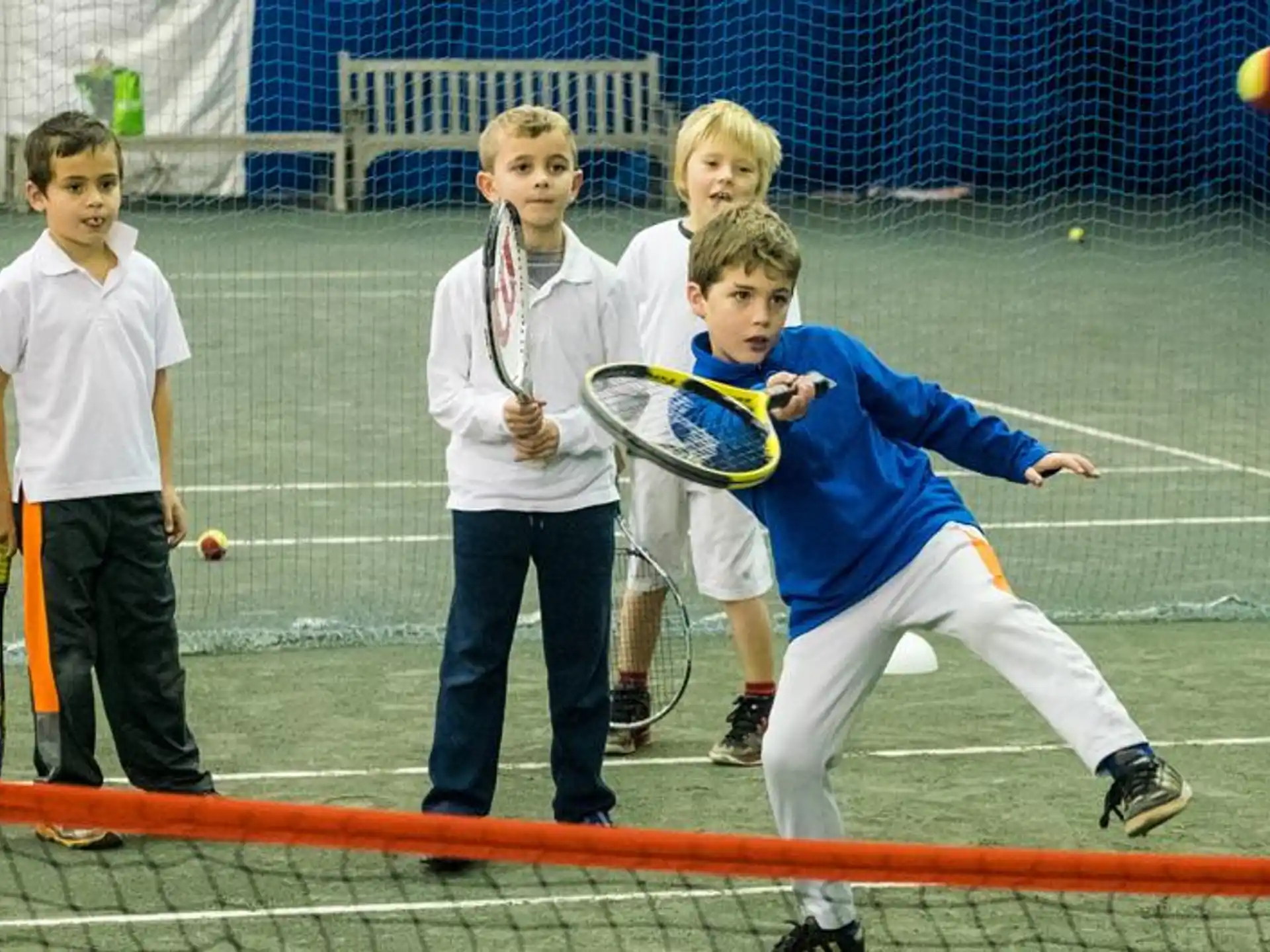 a group of kids playing tennis