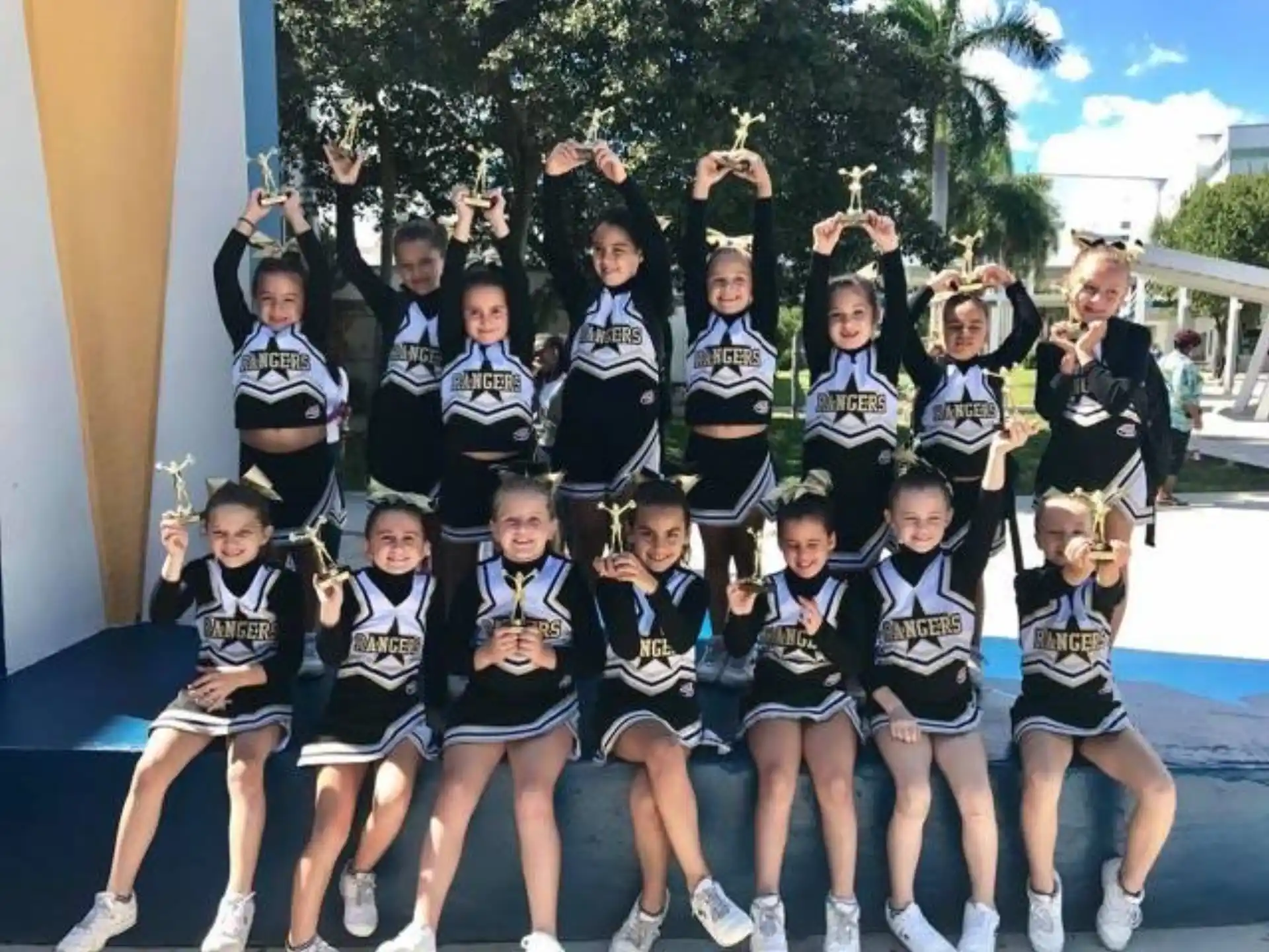 a group of girls in matching black and white uniforms posing for a photo