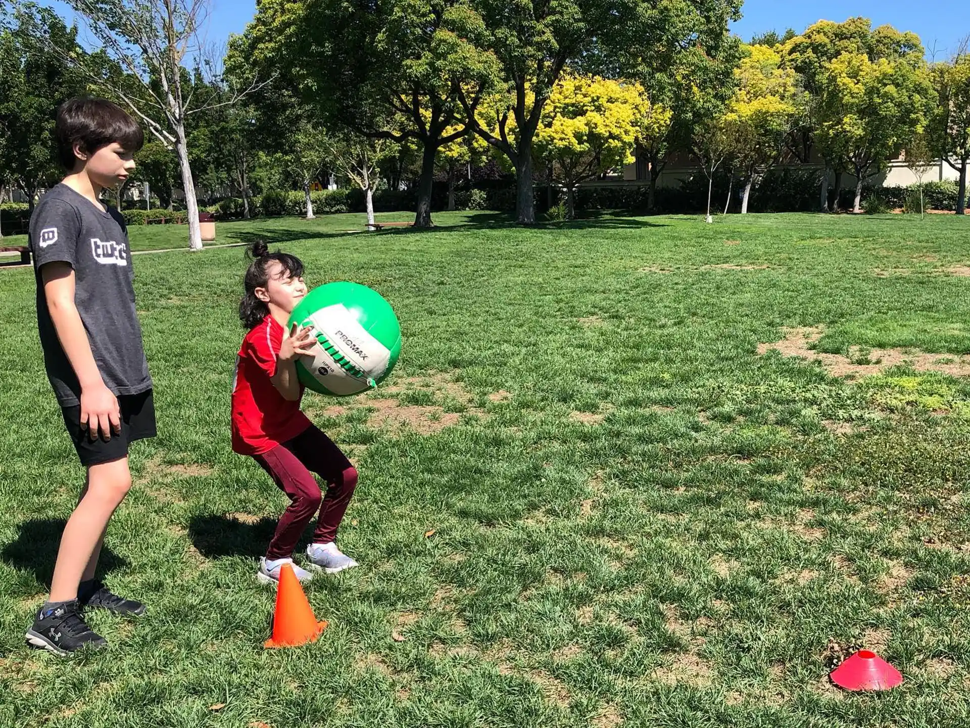 a couple of kids playing with a ball in a grassy field