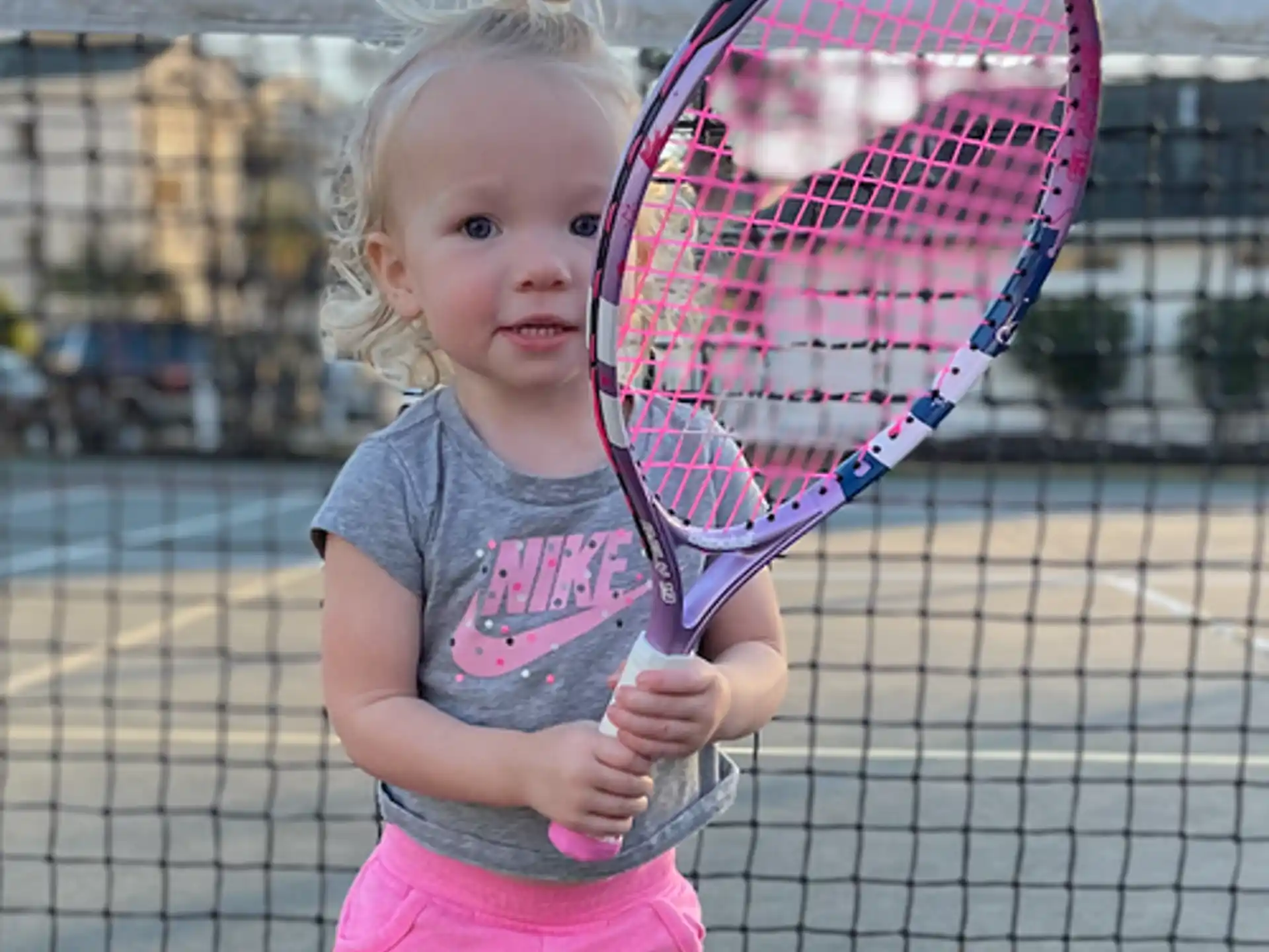 a little girl holding a tennis racket