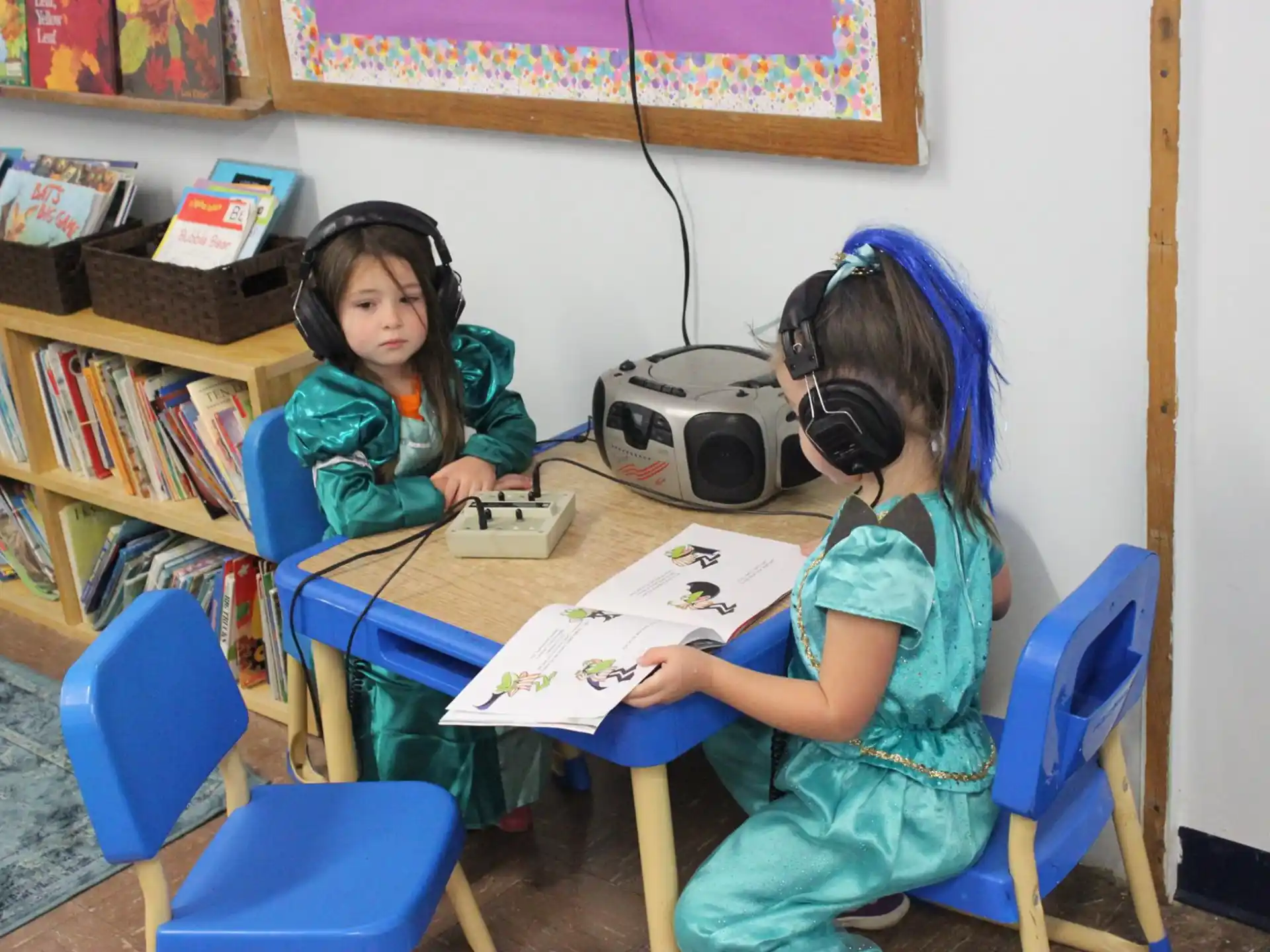 a couple of girls wearing headphones and sitting at a table