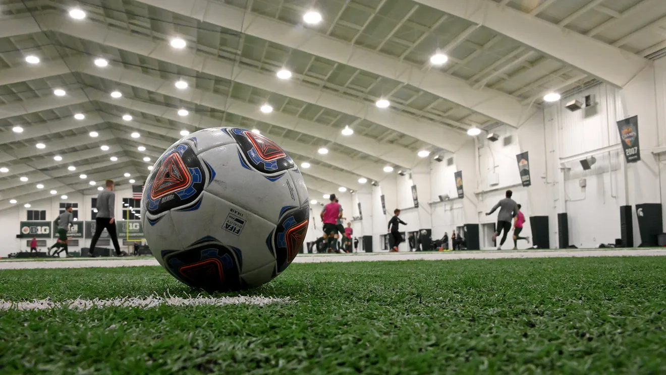 a large white and blue football ball in a large room with people