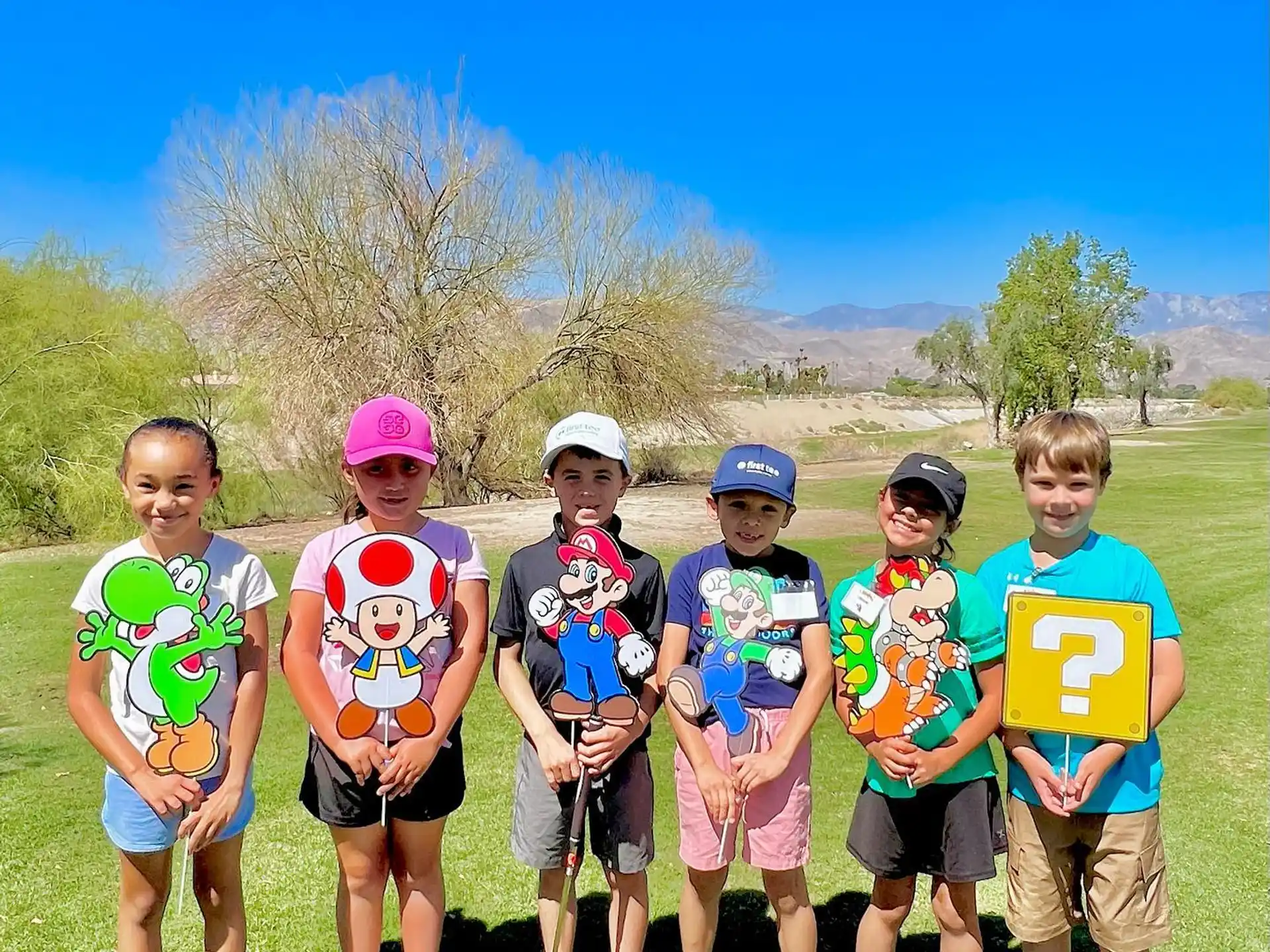 a group of kids wearing matching t-shirts and standing on grass