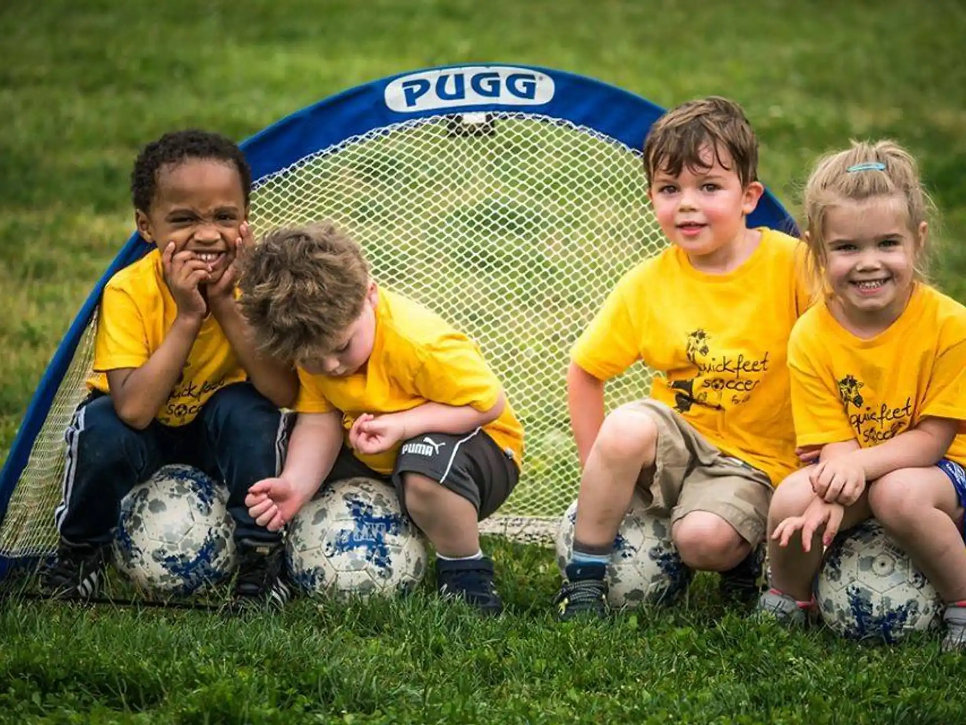 a group of kids sitting on a yellow ball in the grass