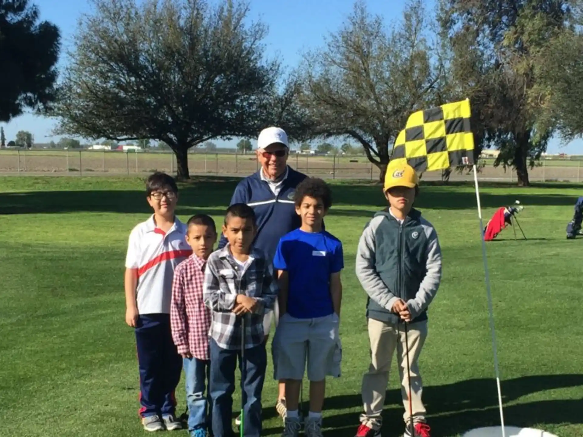 a group of people standing on a golf course with a flag