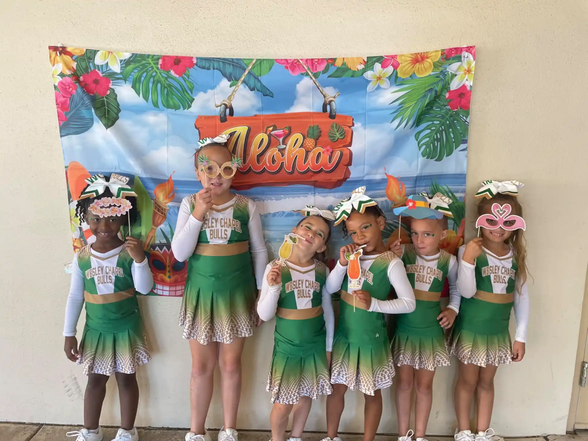 a group of children in green and white dresses with a sign