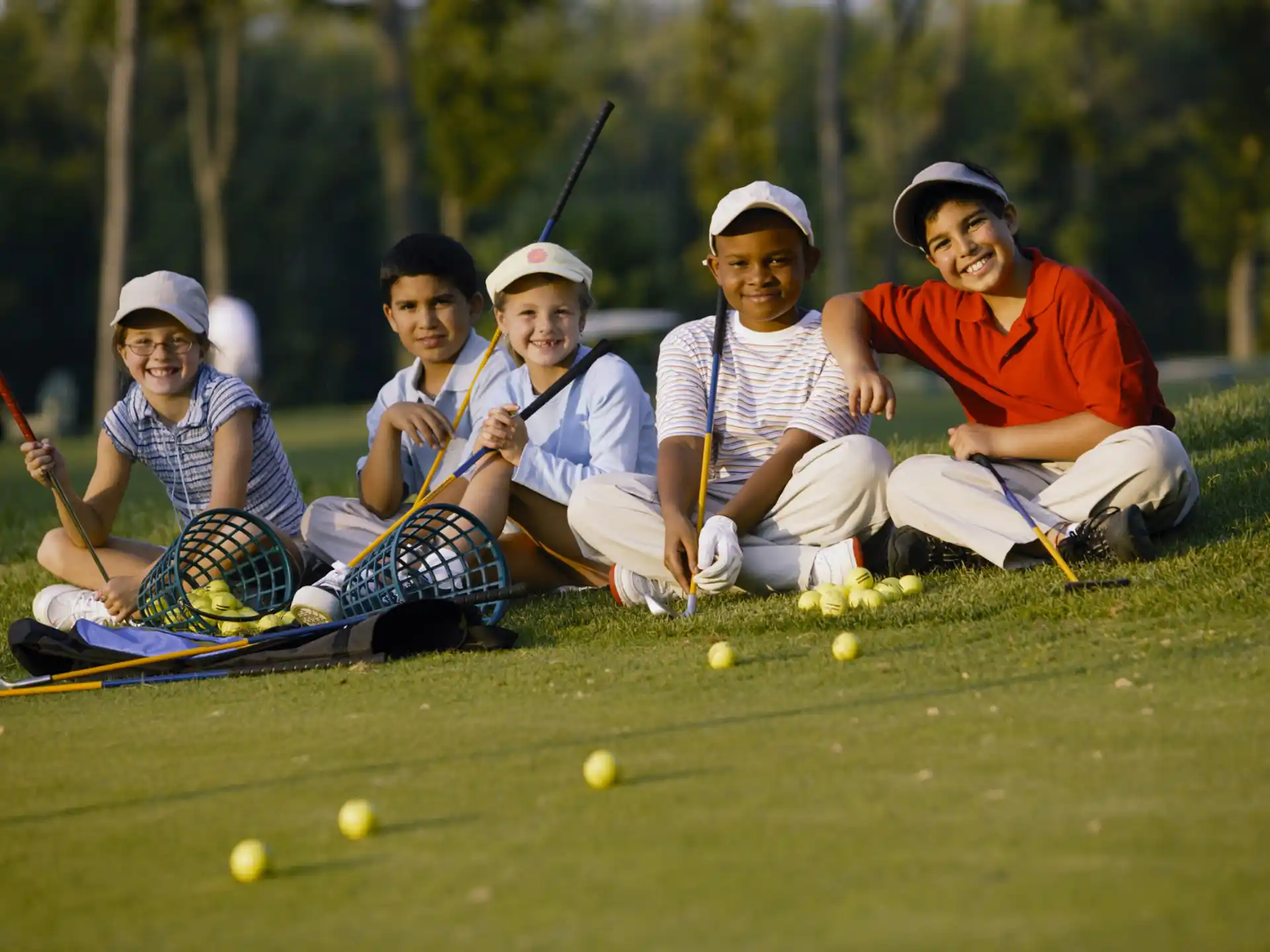 a group of people sitting on the grass with golf clubs