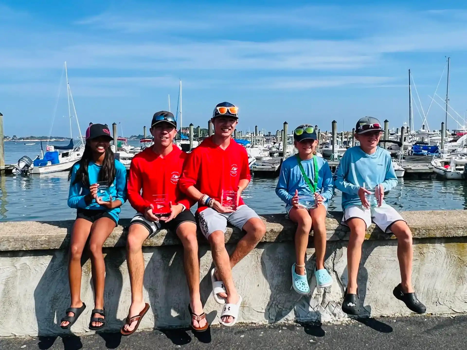 a group of people sitting on a bench in front of a body of water