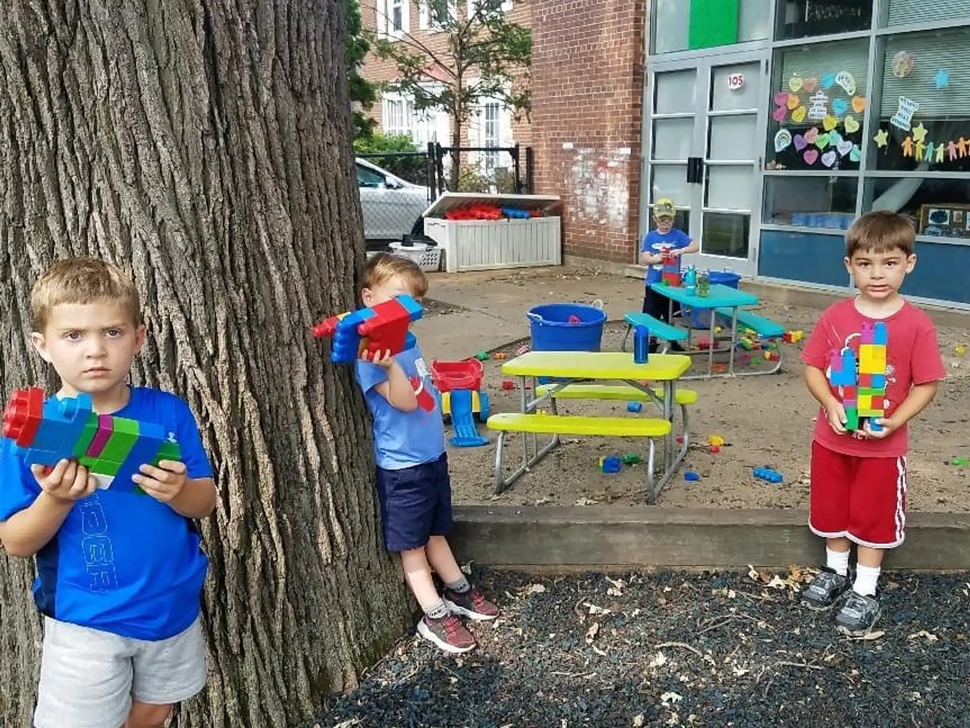 a group of boys standing next to a tree and a building