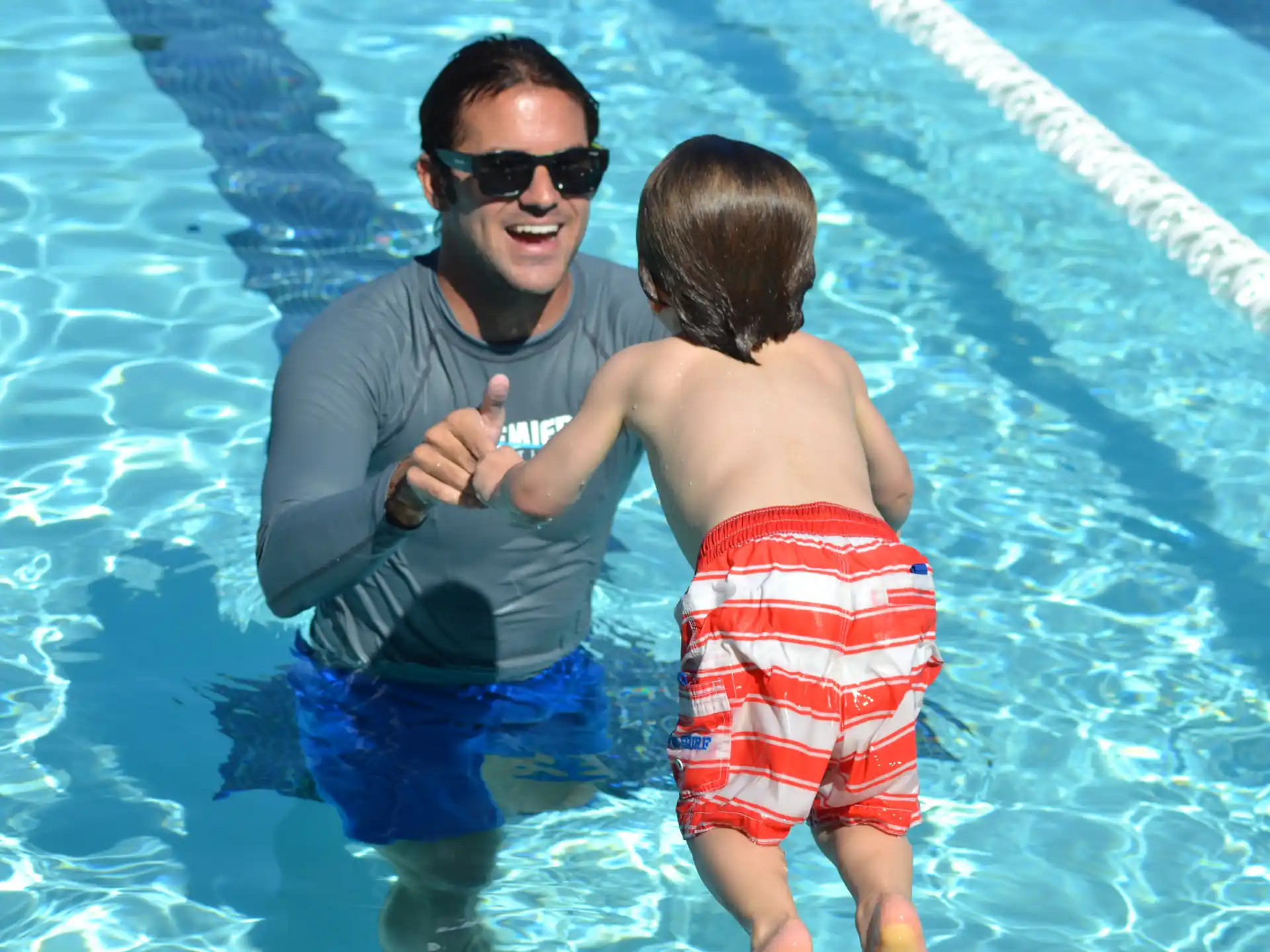 a person holding a baby in a pool