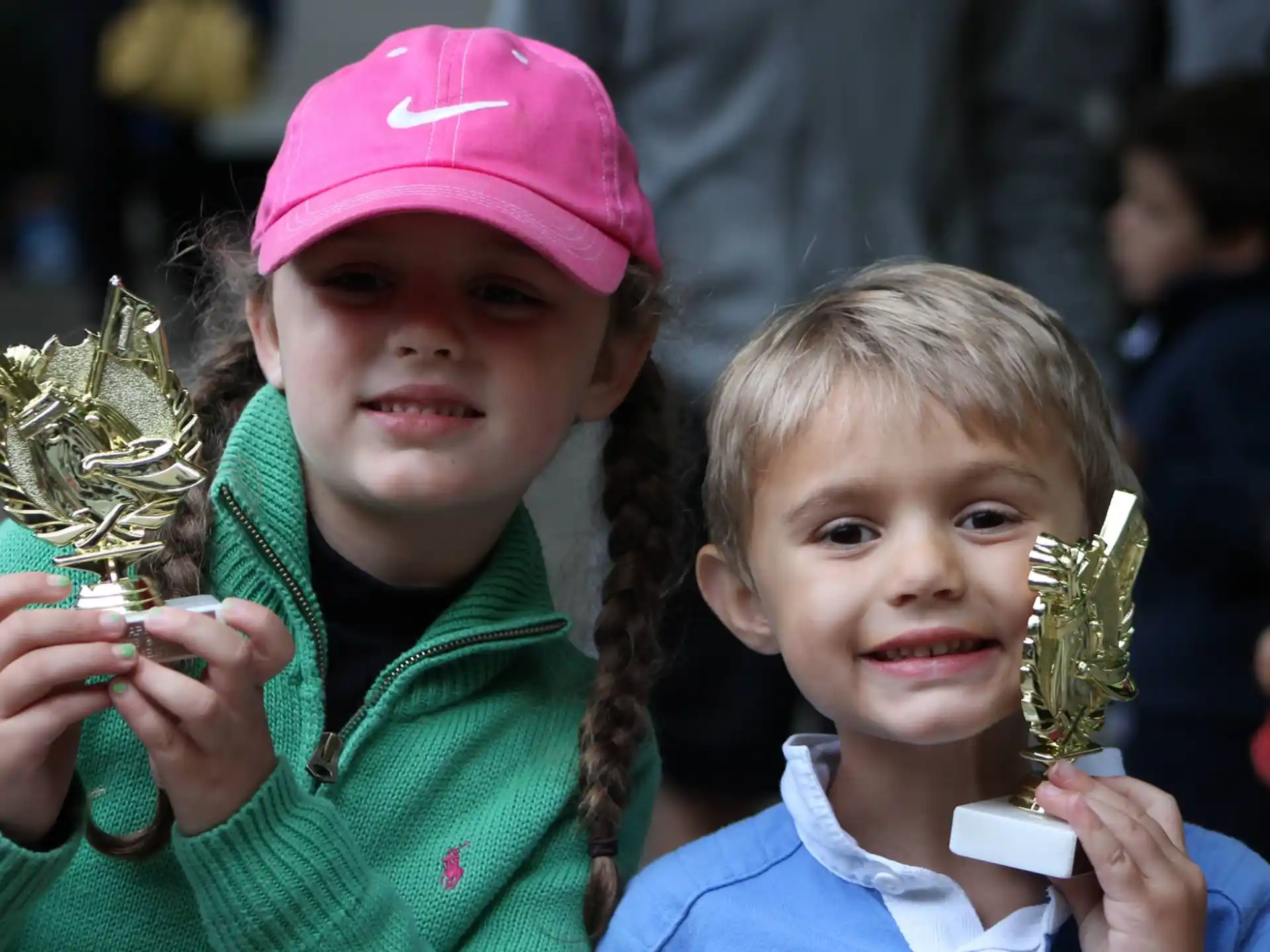 a couple of children holding gold and silver trophies