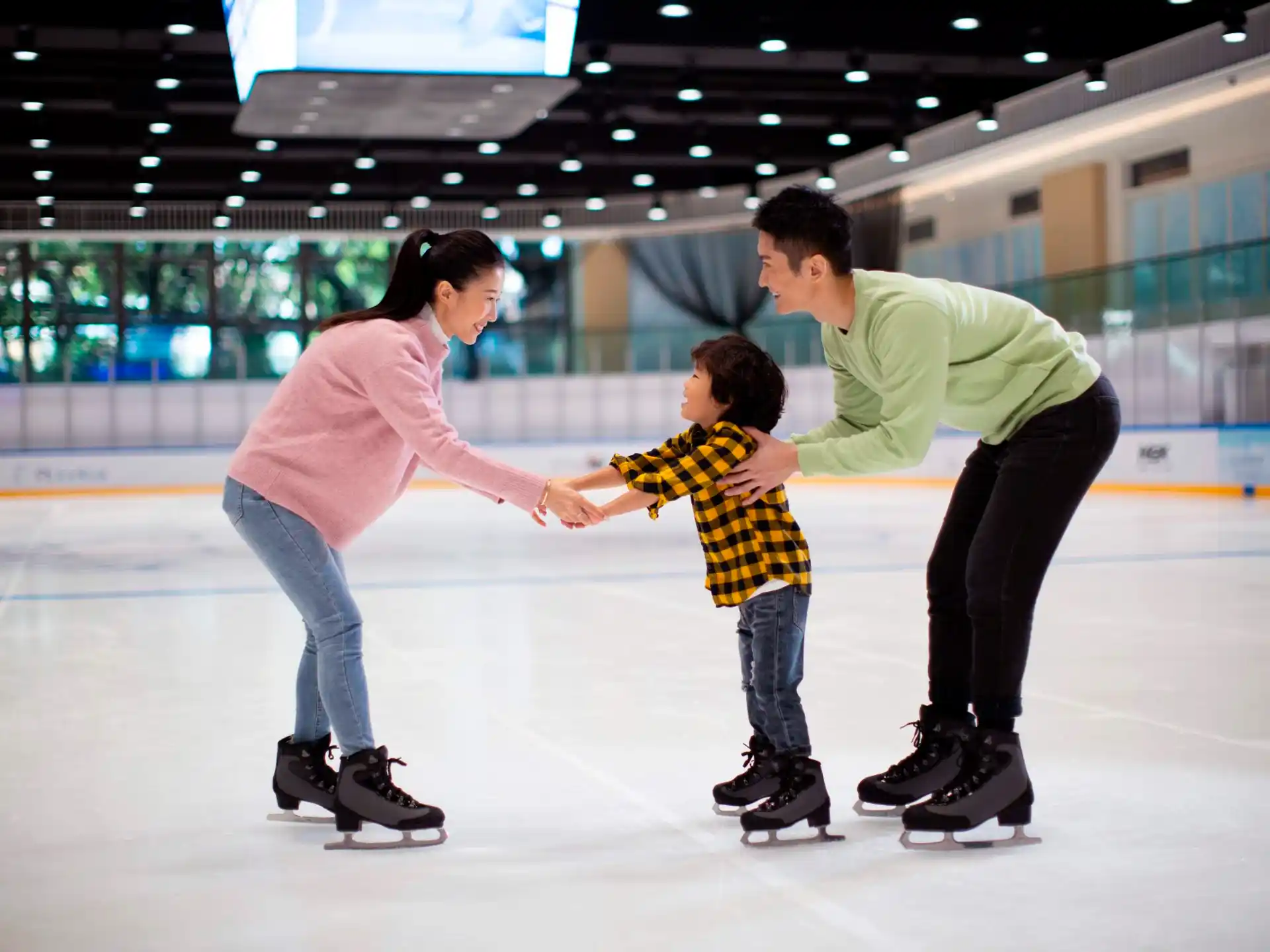 a man and woman holding hands with a child on an ice rink