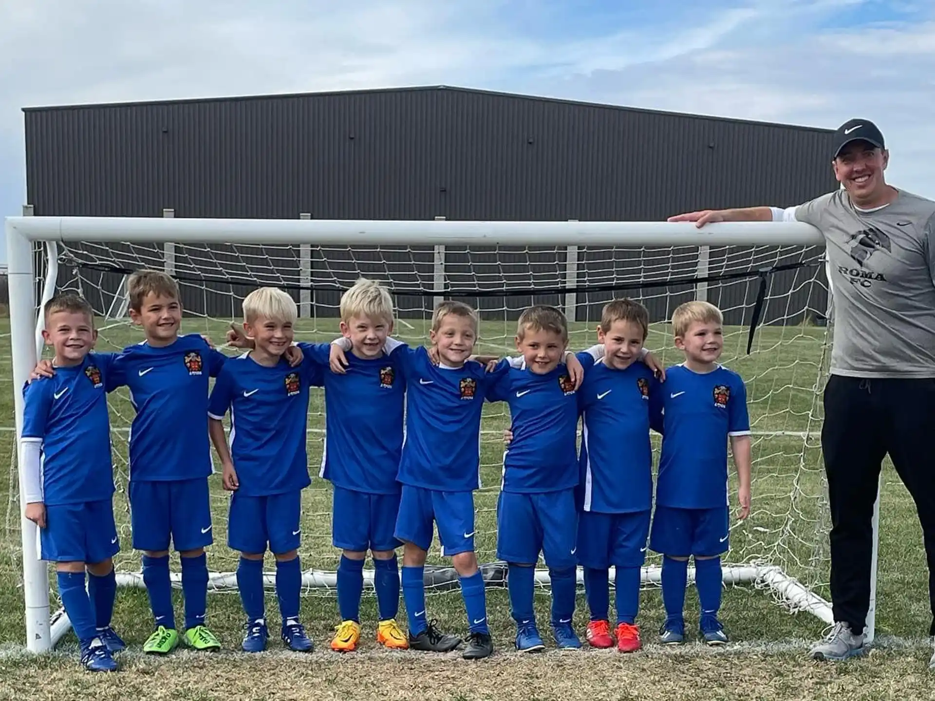 a person standing with a group of kids in front of a white structure