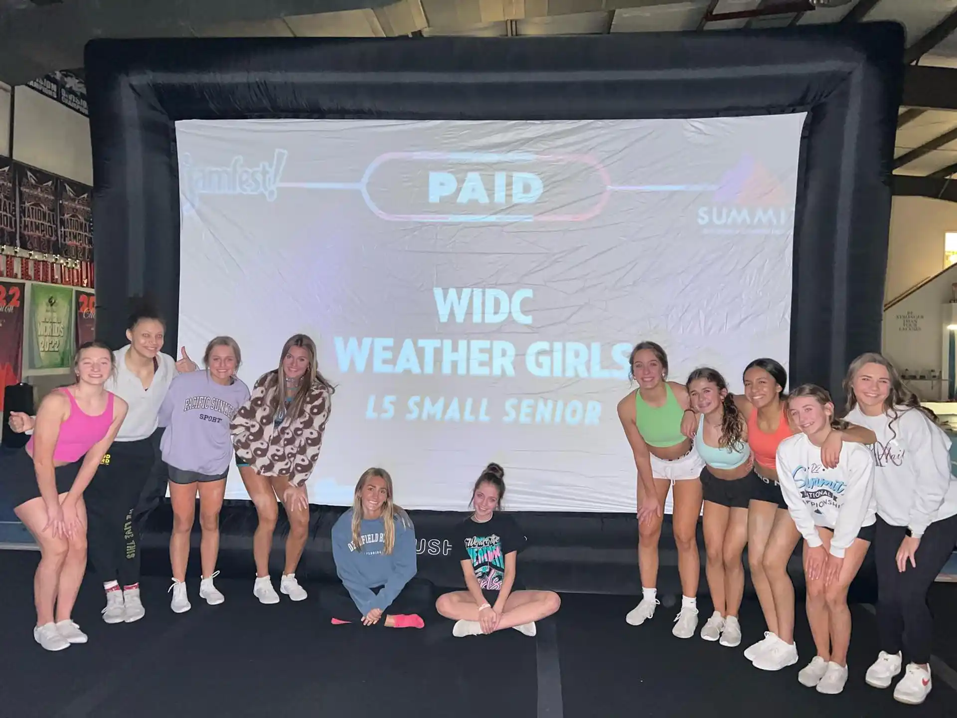 a group of people posing for a photo in front of a large screen