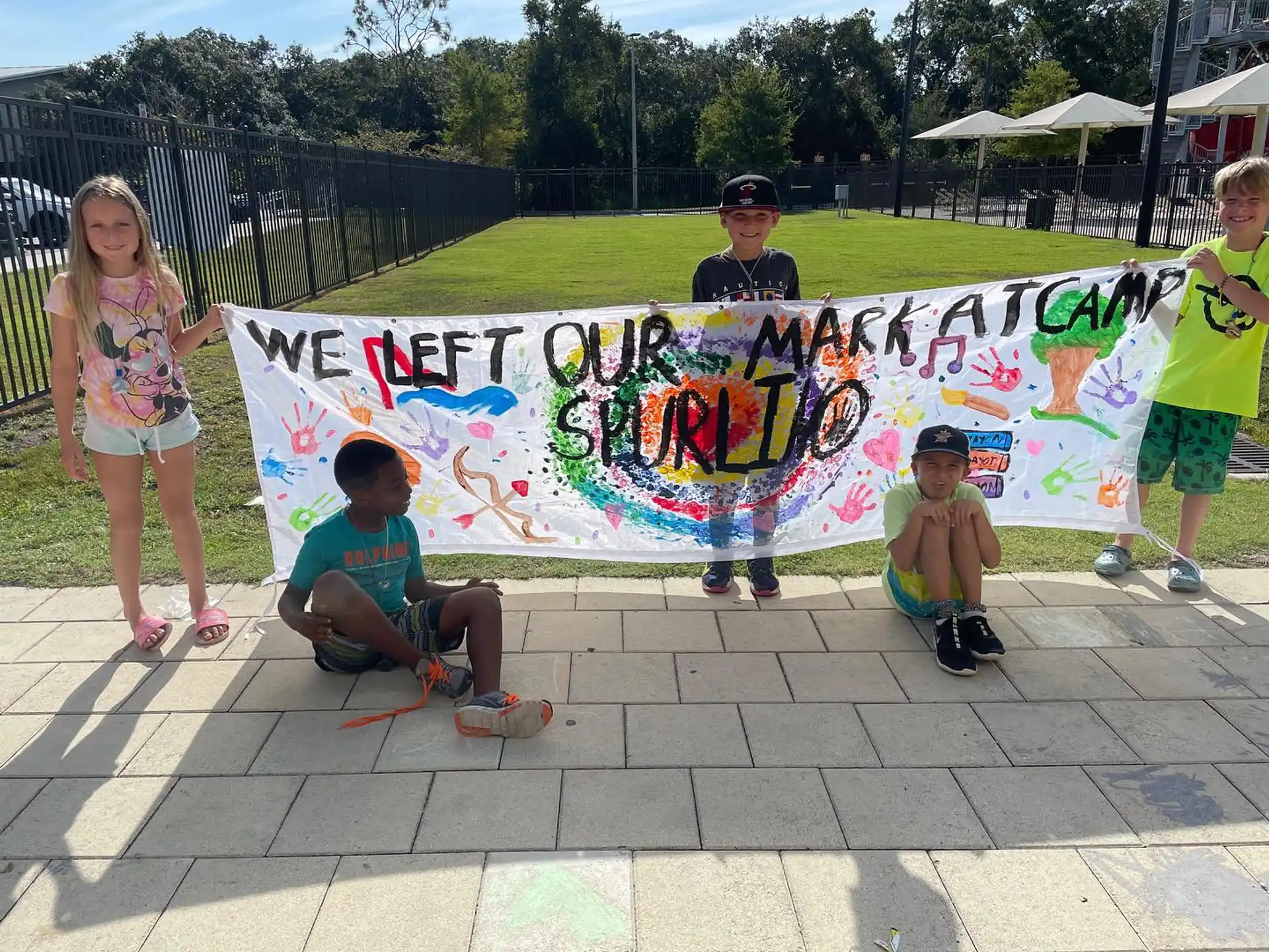 a group of kids posing for a picture next to a large colorful sculpture
