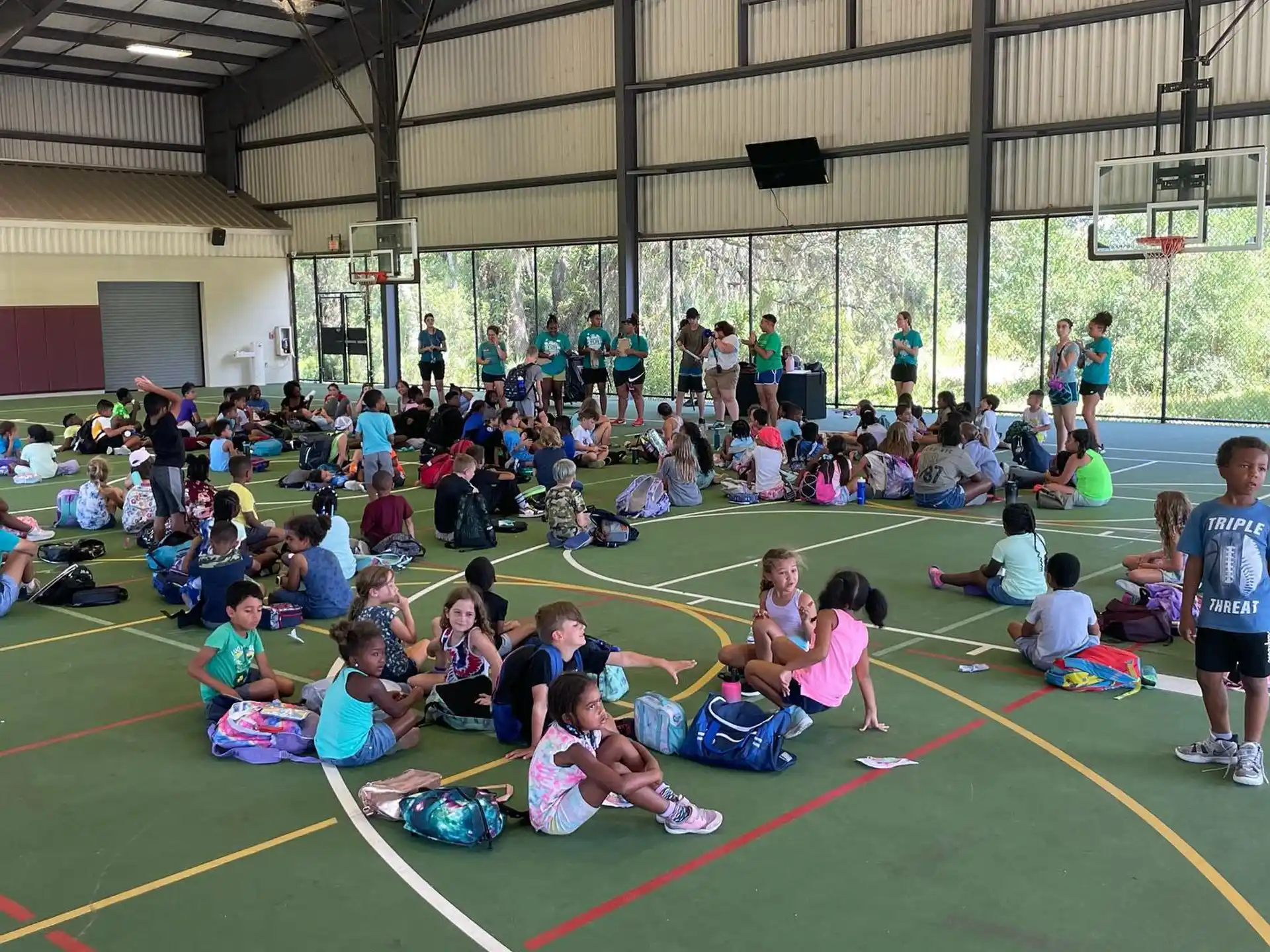 a group of people sitting on the ground in a gym