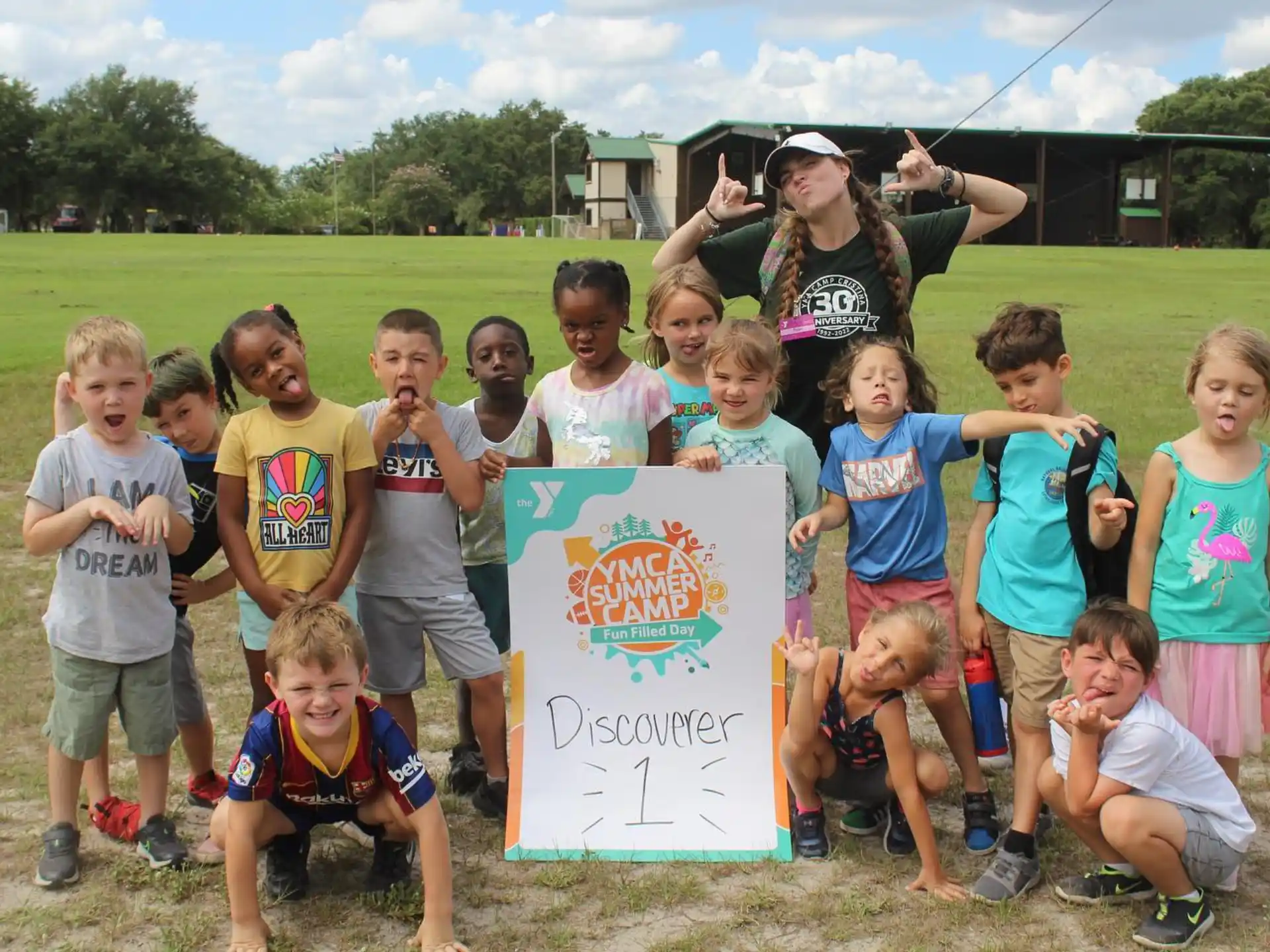 a group of children posing for a photo with a sign
