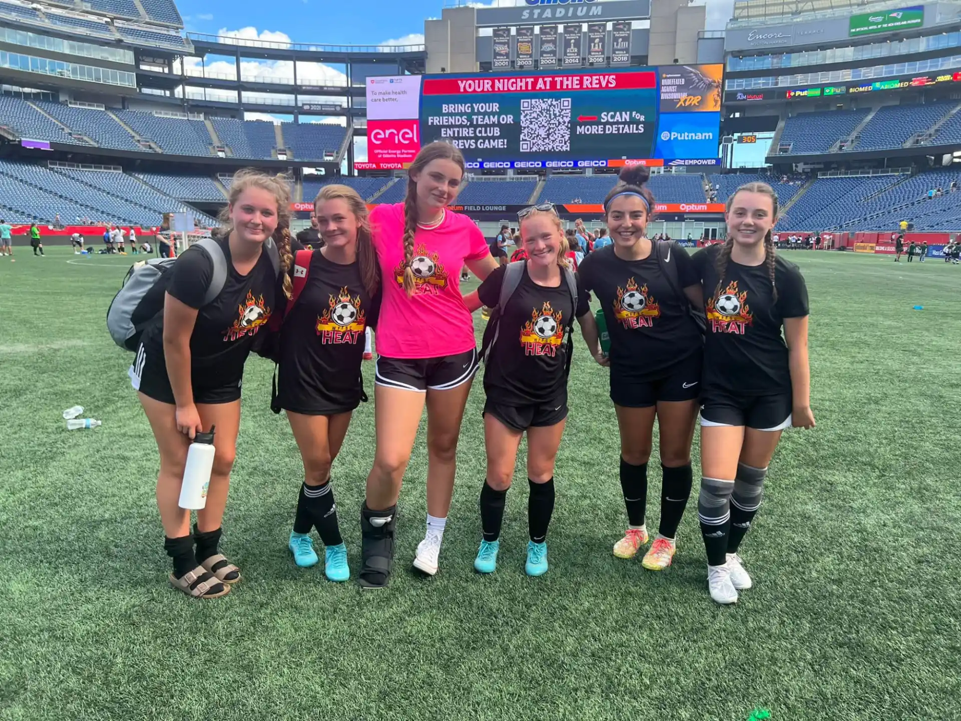 a group of women posing for a photo on a football field