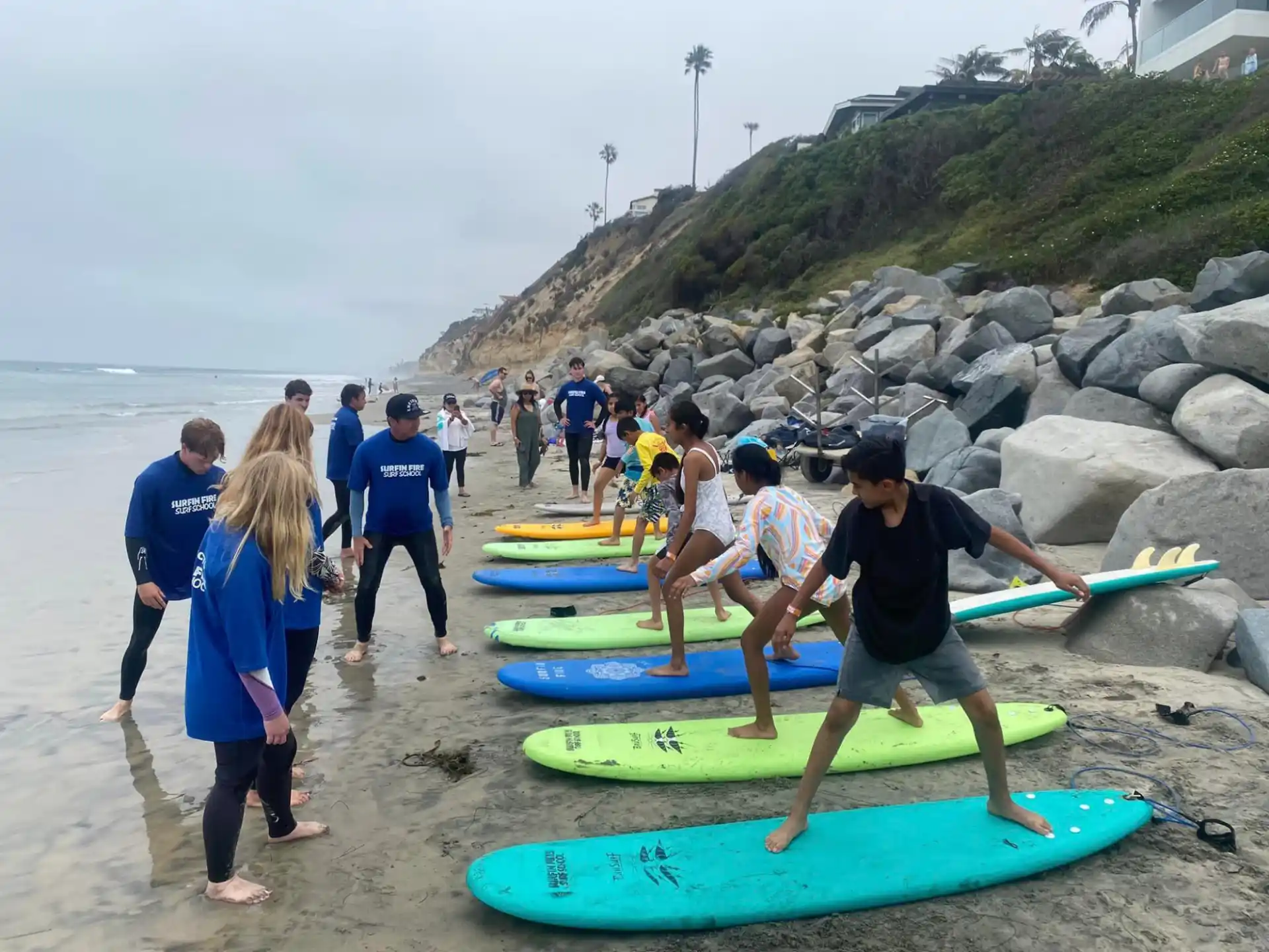 a group of people stand on the beach with surfboards