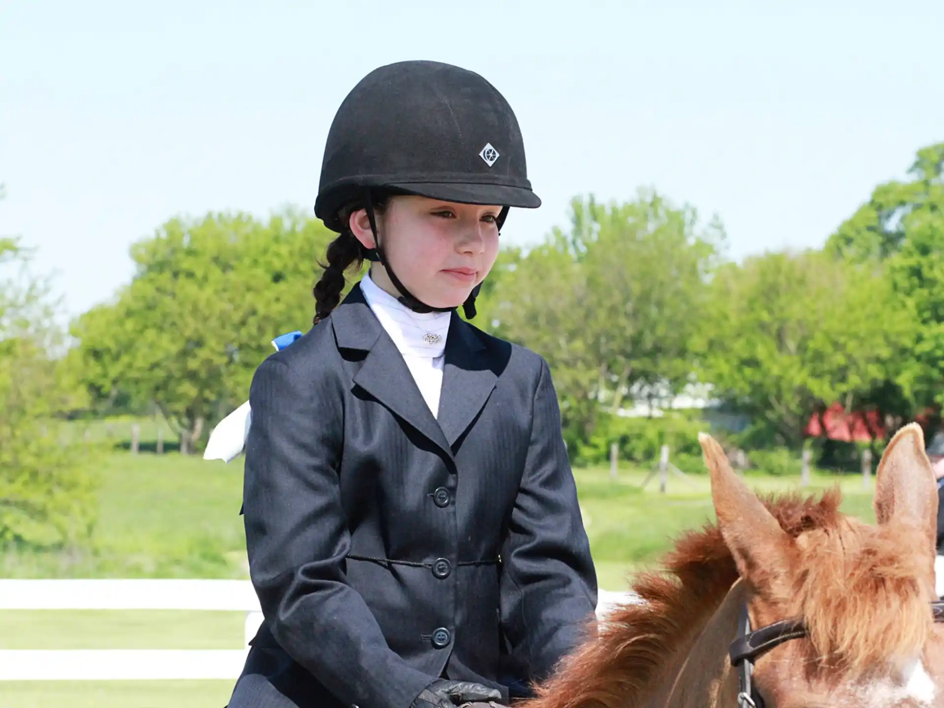 a boy in a uniform standing next to a horse