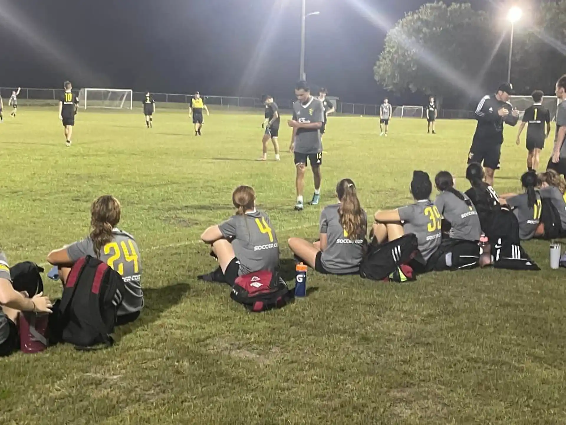a group of people sitting on the grass in front of a football field