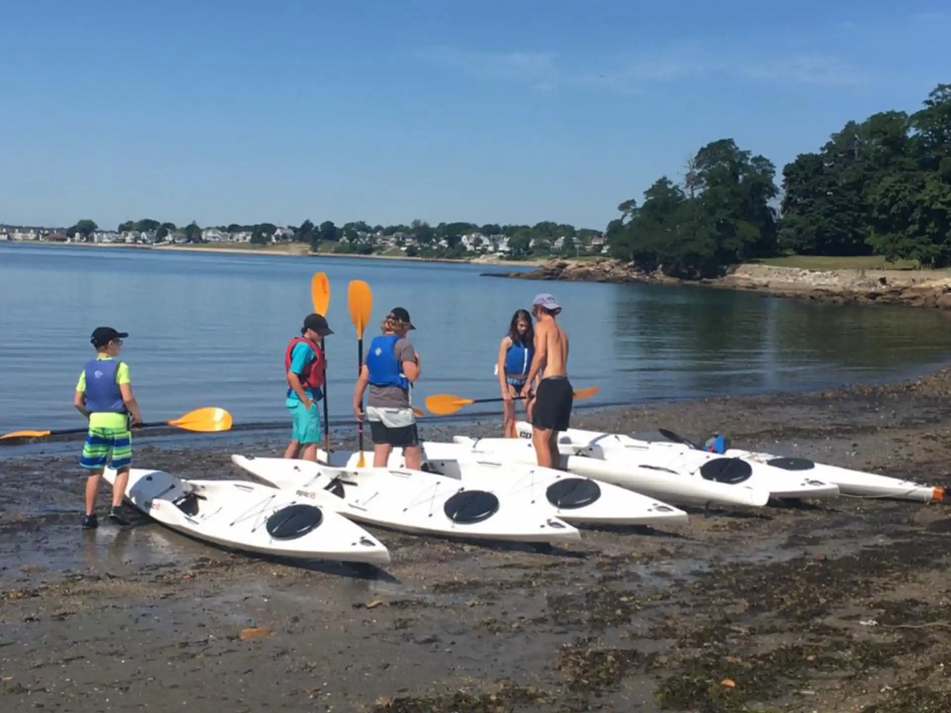 a group of people standing next to a row of jet skis