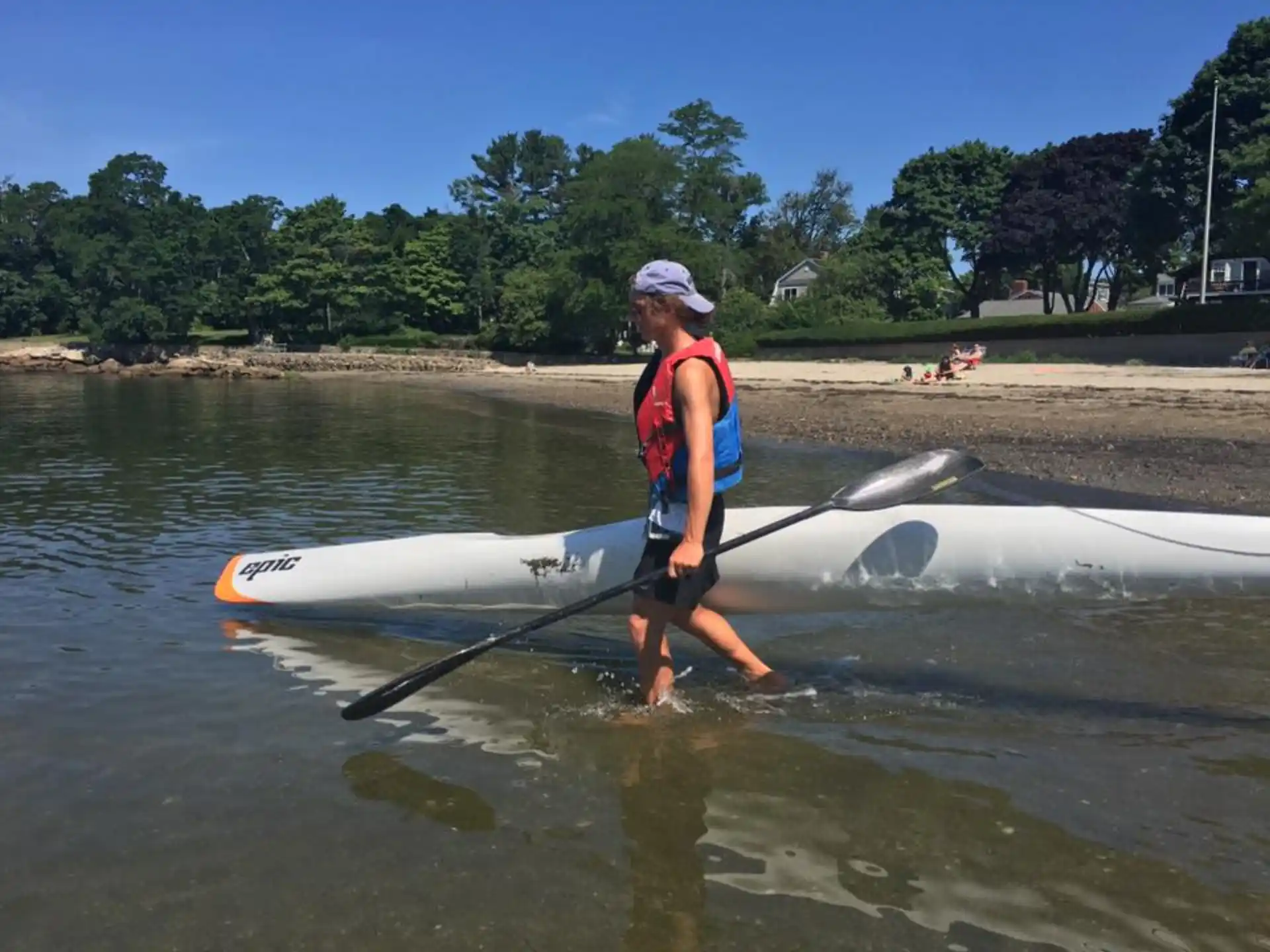 a man holding a paddle and standing in water with a surfboard