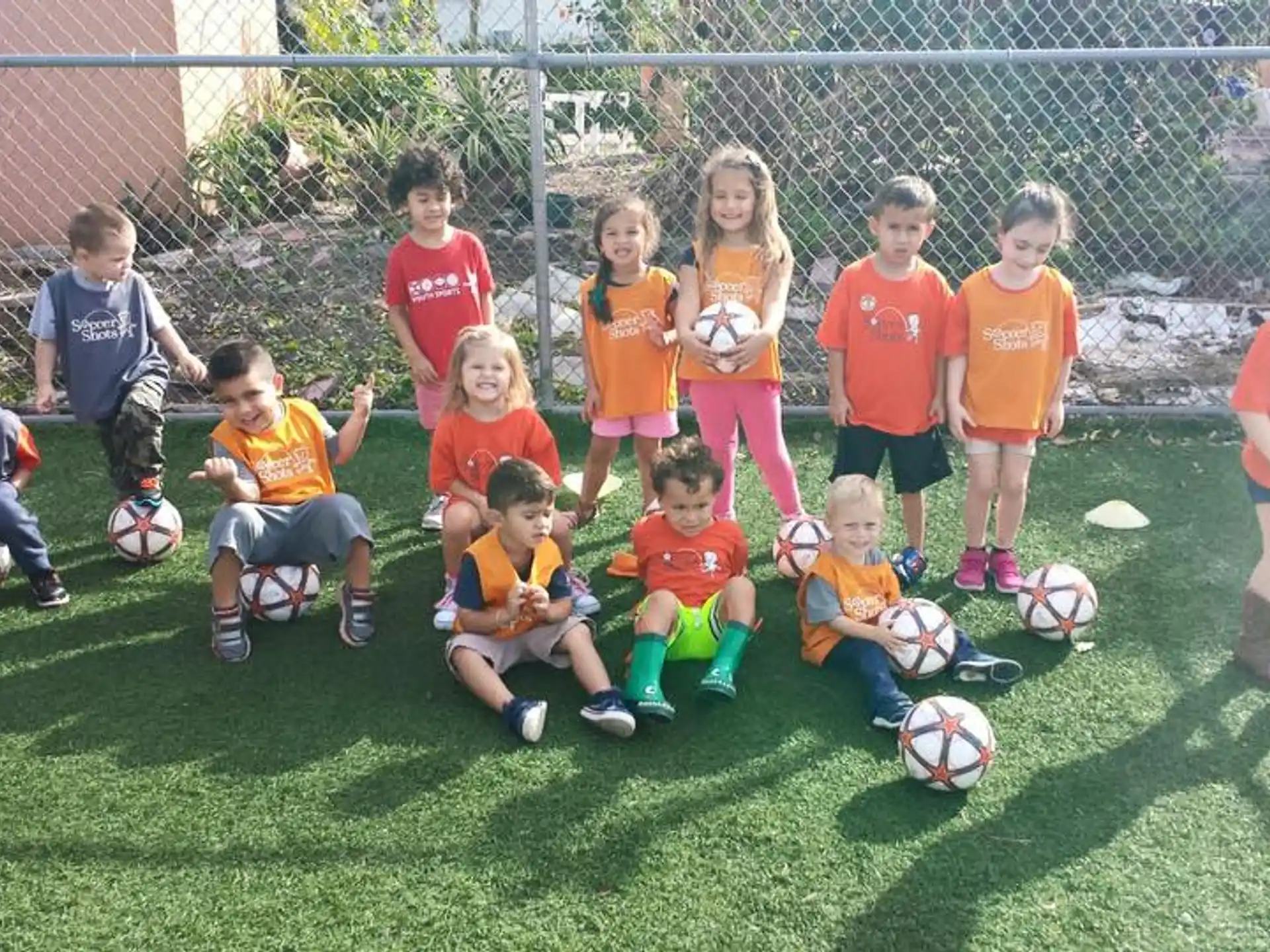 a group of kids posing for a picture with football balls