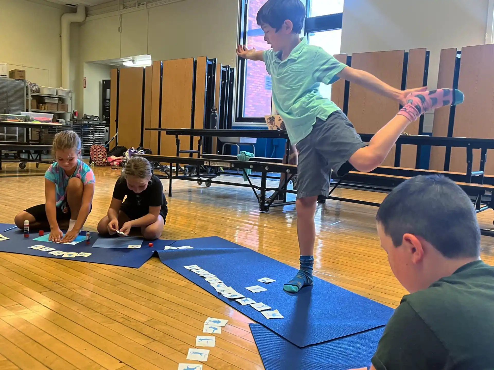 a boy standing on a mat in a room with other people