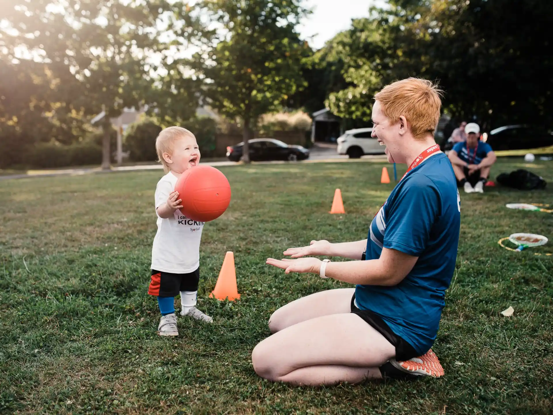 a person and a child playing with a ball in a park