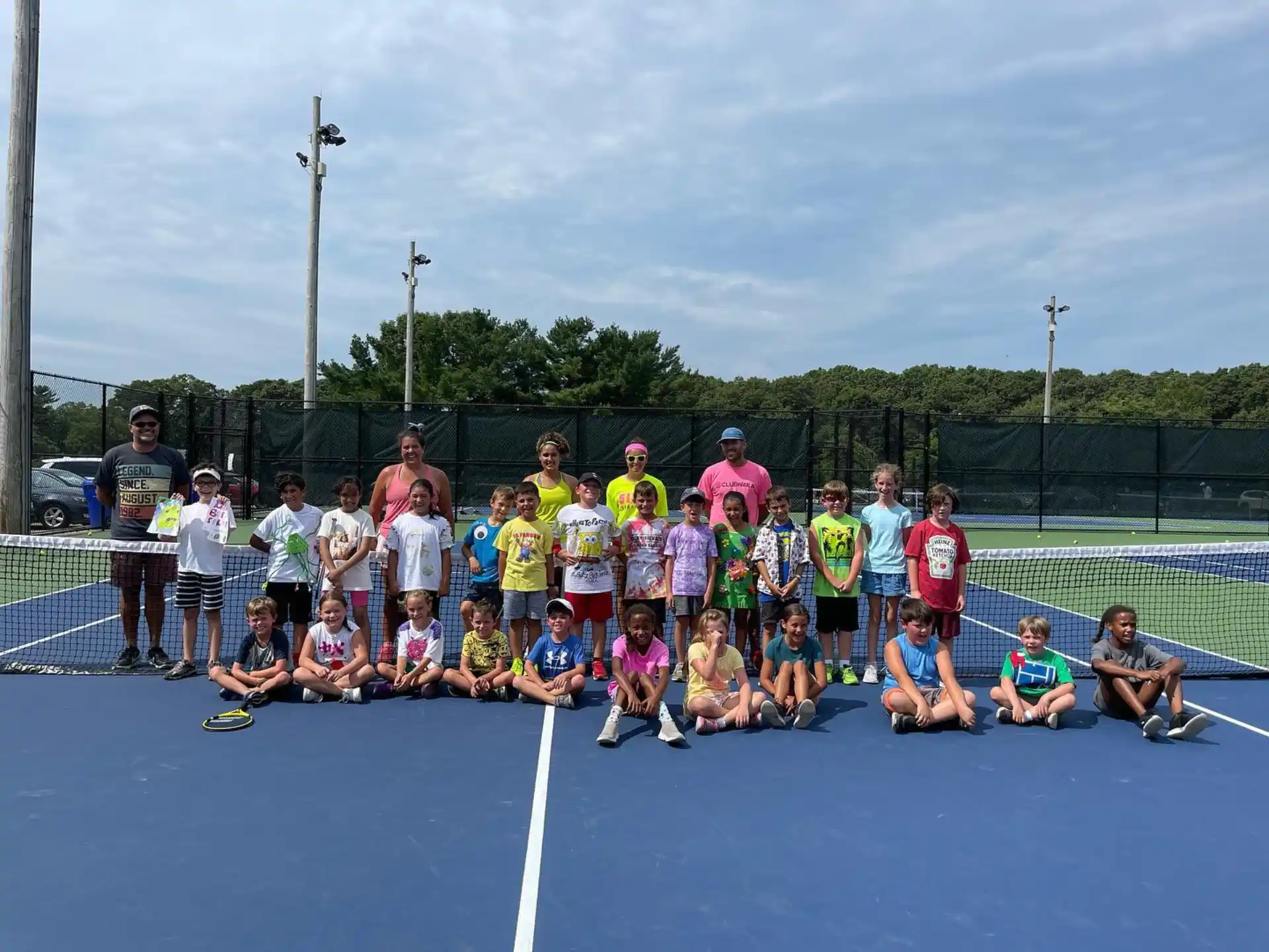 a group of people posing for a photo on a tennis court