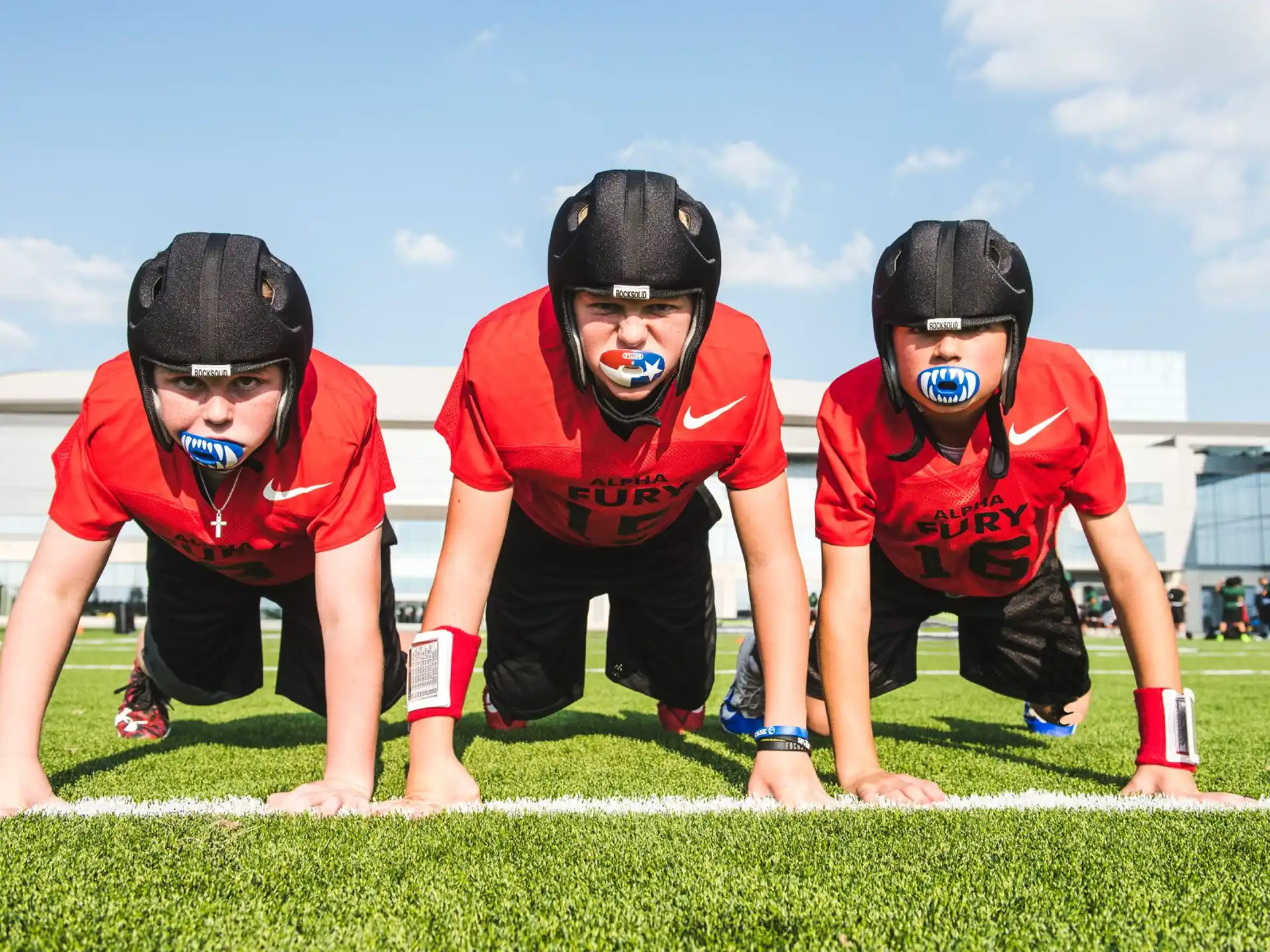 a group of people wearing red and black uniforms and masks on a grass field