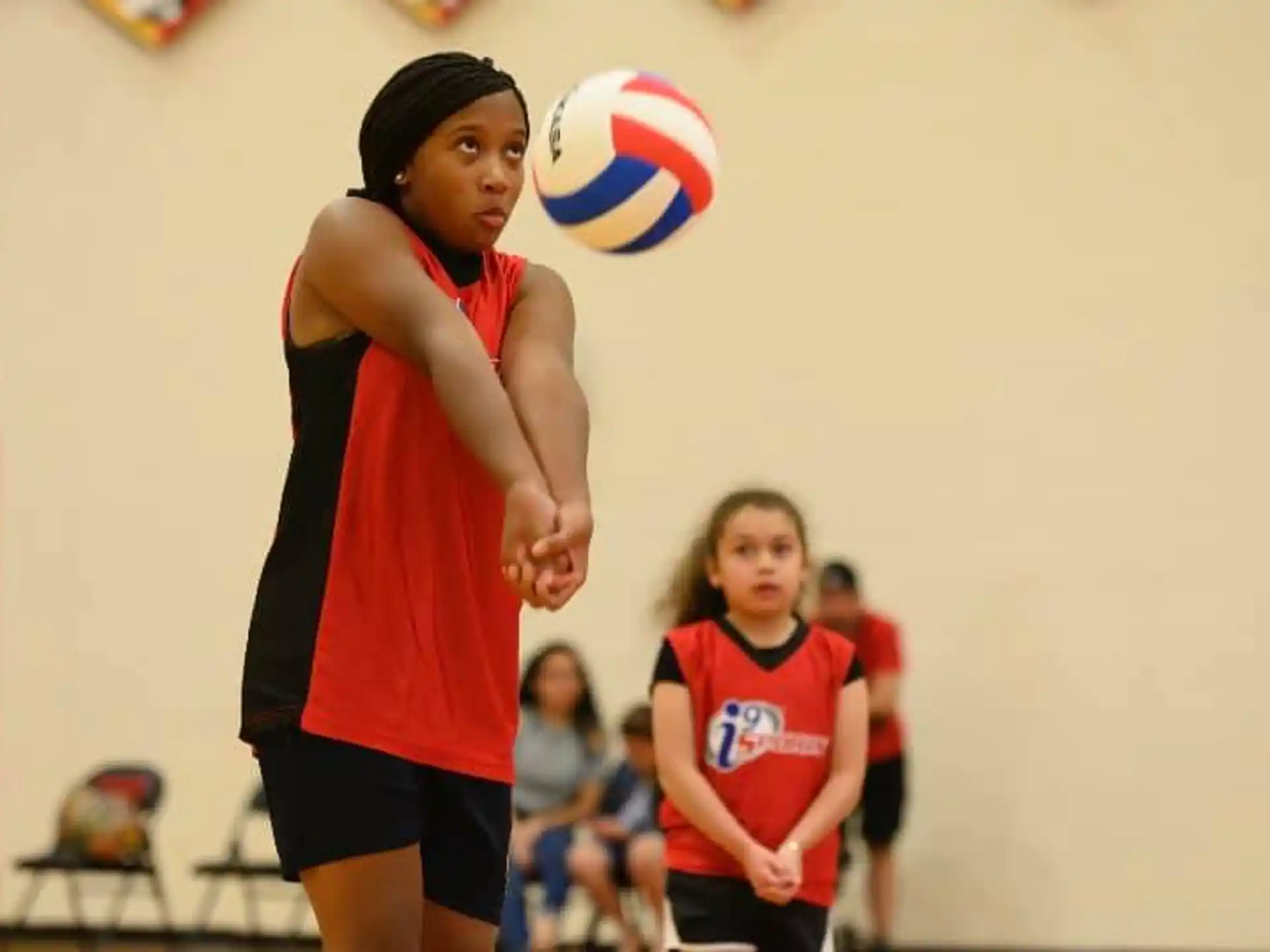 a woman in a red shirt and black shorts with a ball in the air