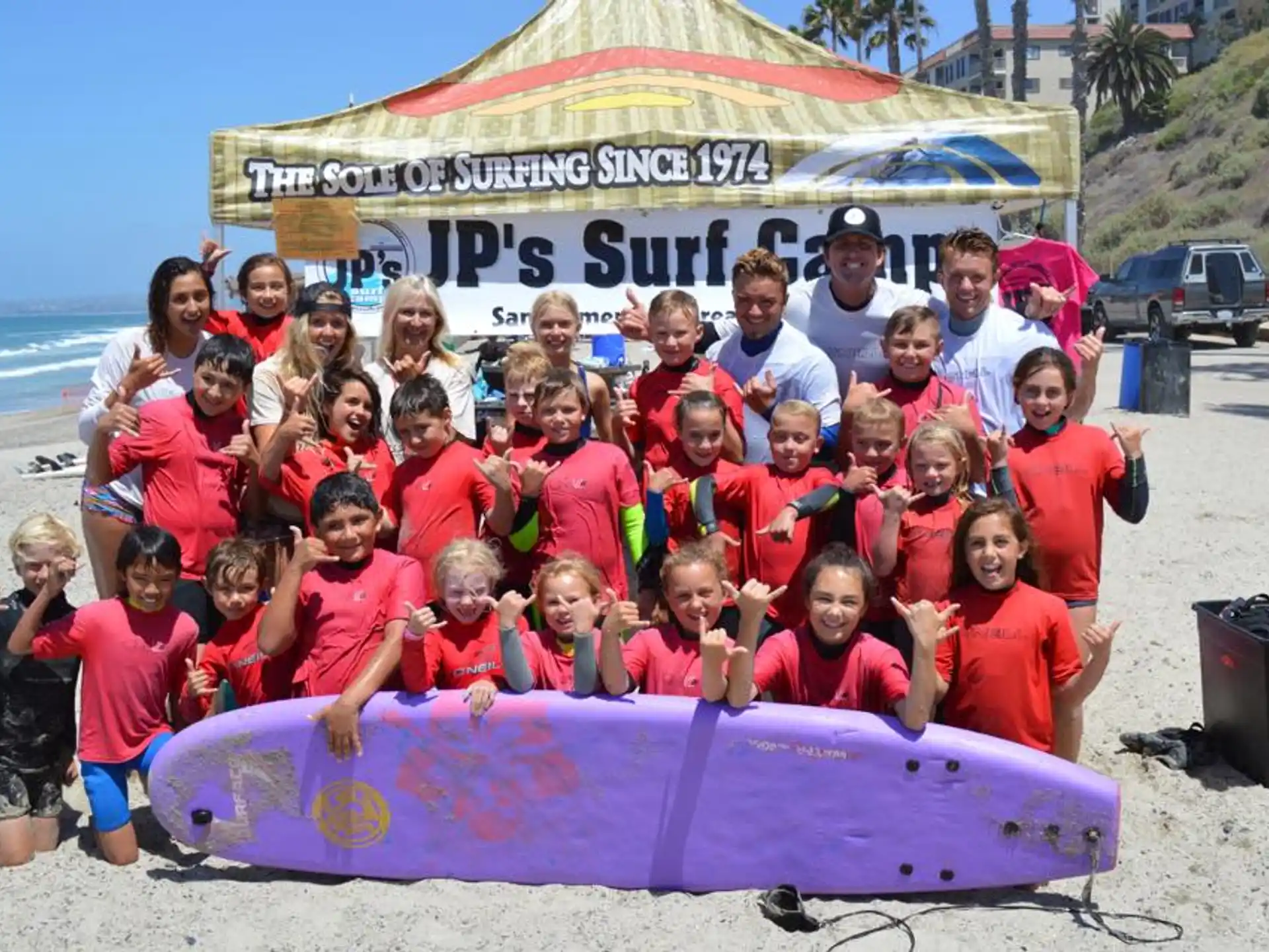 a group of people posing for a photo with a surfboard